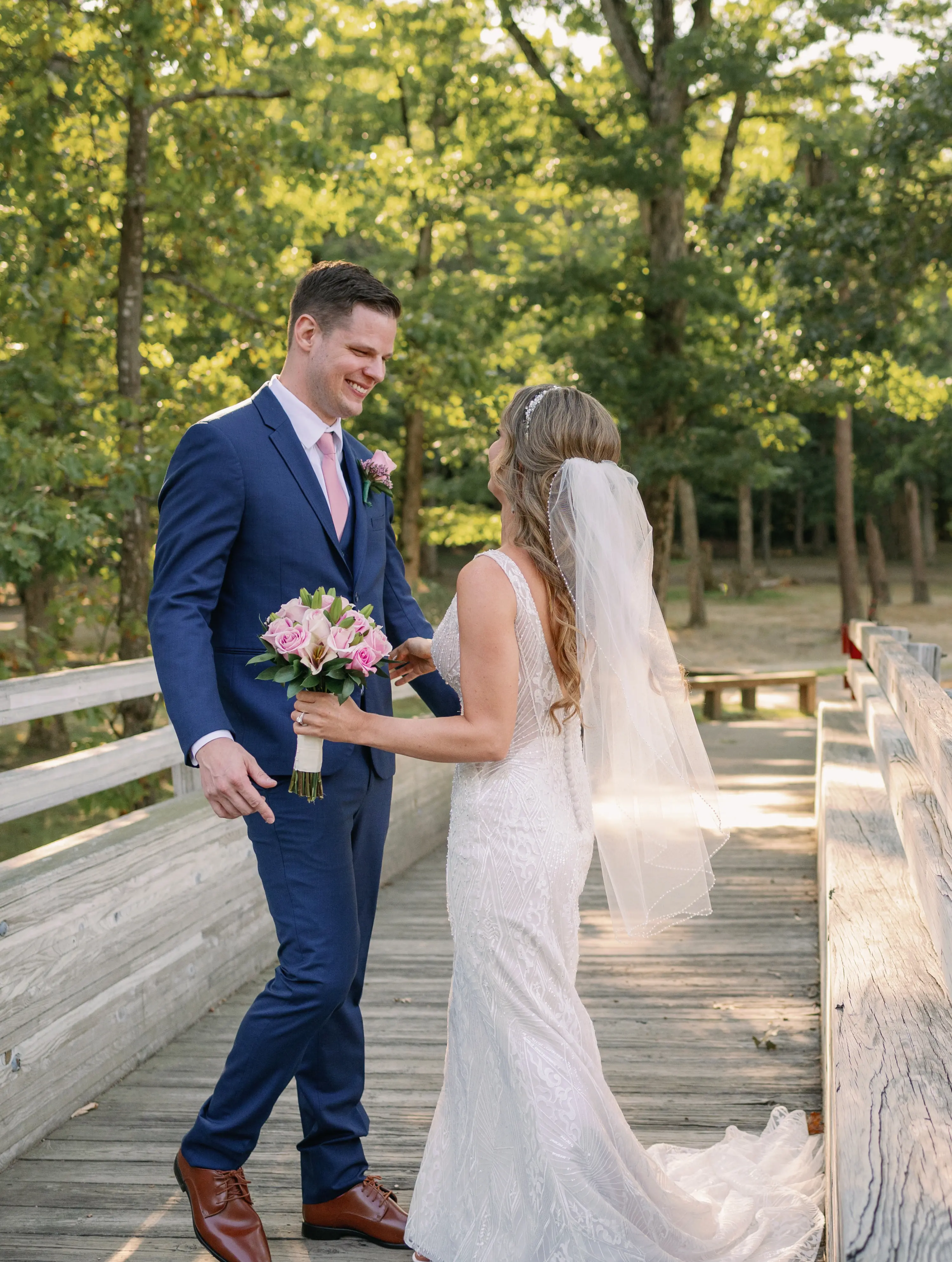 Bride and groom looking at each other smiling on a wooden pier.