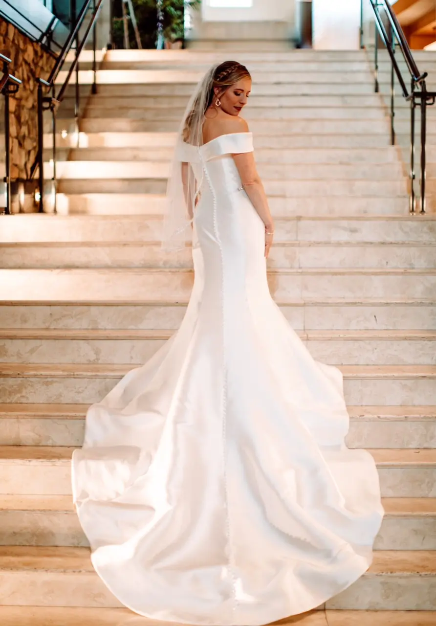 Bride facing up stairs with her wedding dress train cascading down them.
