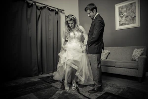 Bride Wearing Boho A-Line Wedding Dress Called Stevie By Maggie Sottero With Groom Putting On Her Shoes