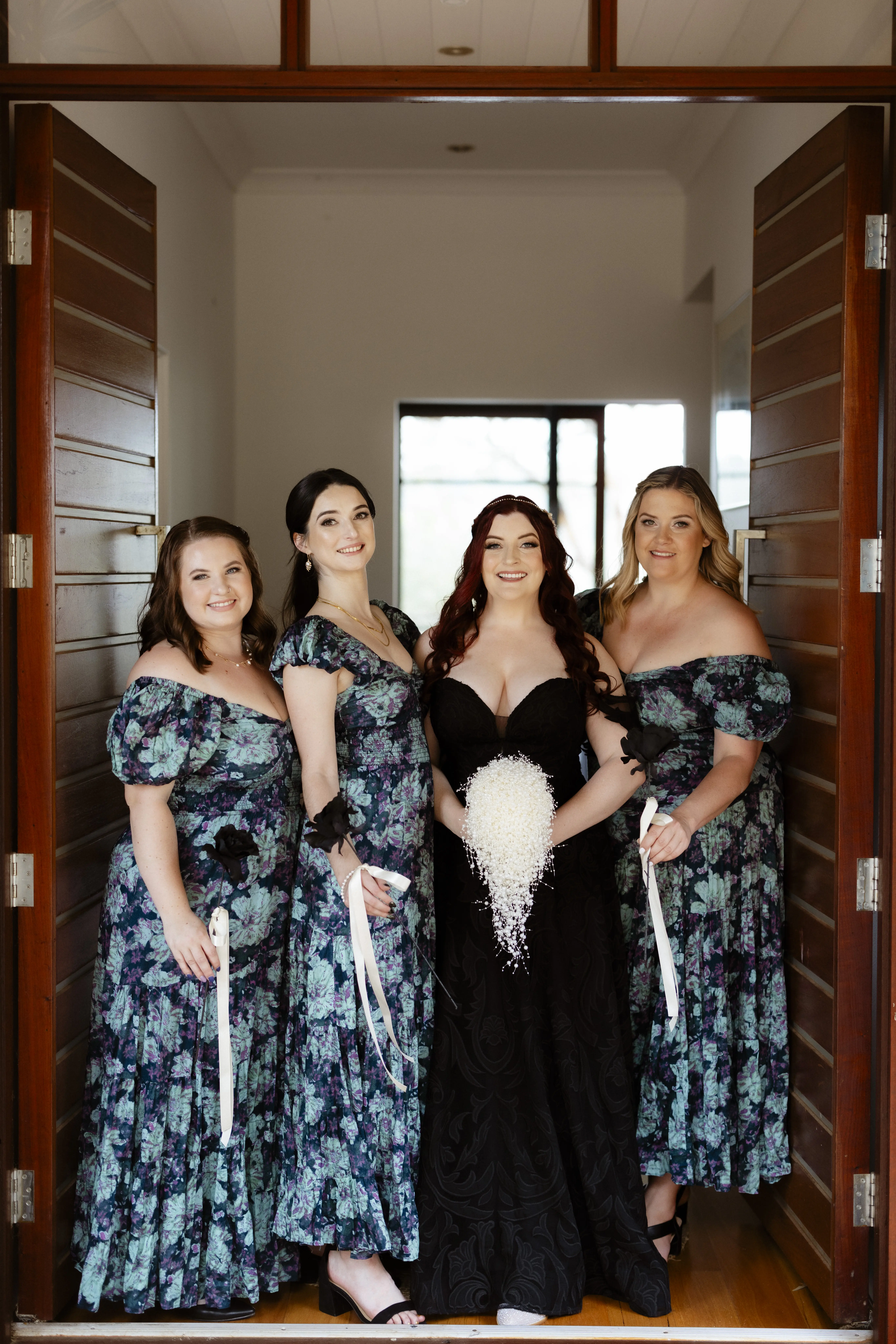 Bride Wearing Black Lace Wedding Dress Called Penny By Maggie Sottero With Bridesmaids In Blue and Black Floral Dresses