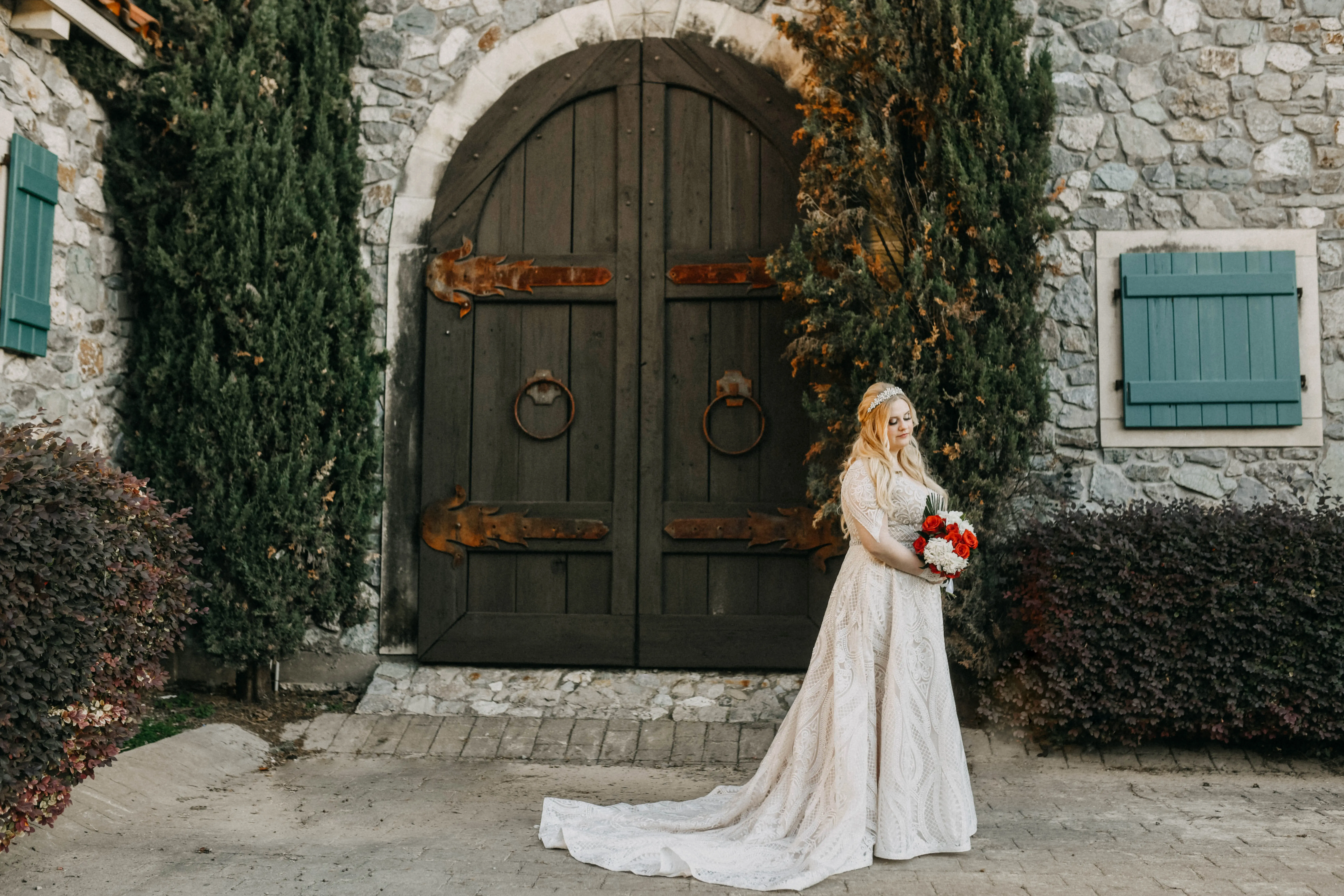 Bride wearing wedding dress called Roxanne standing outside by large green arch doors.