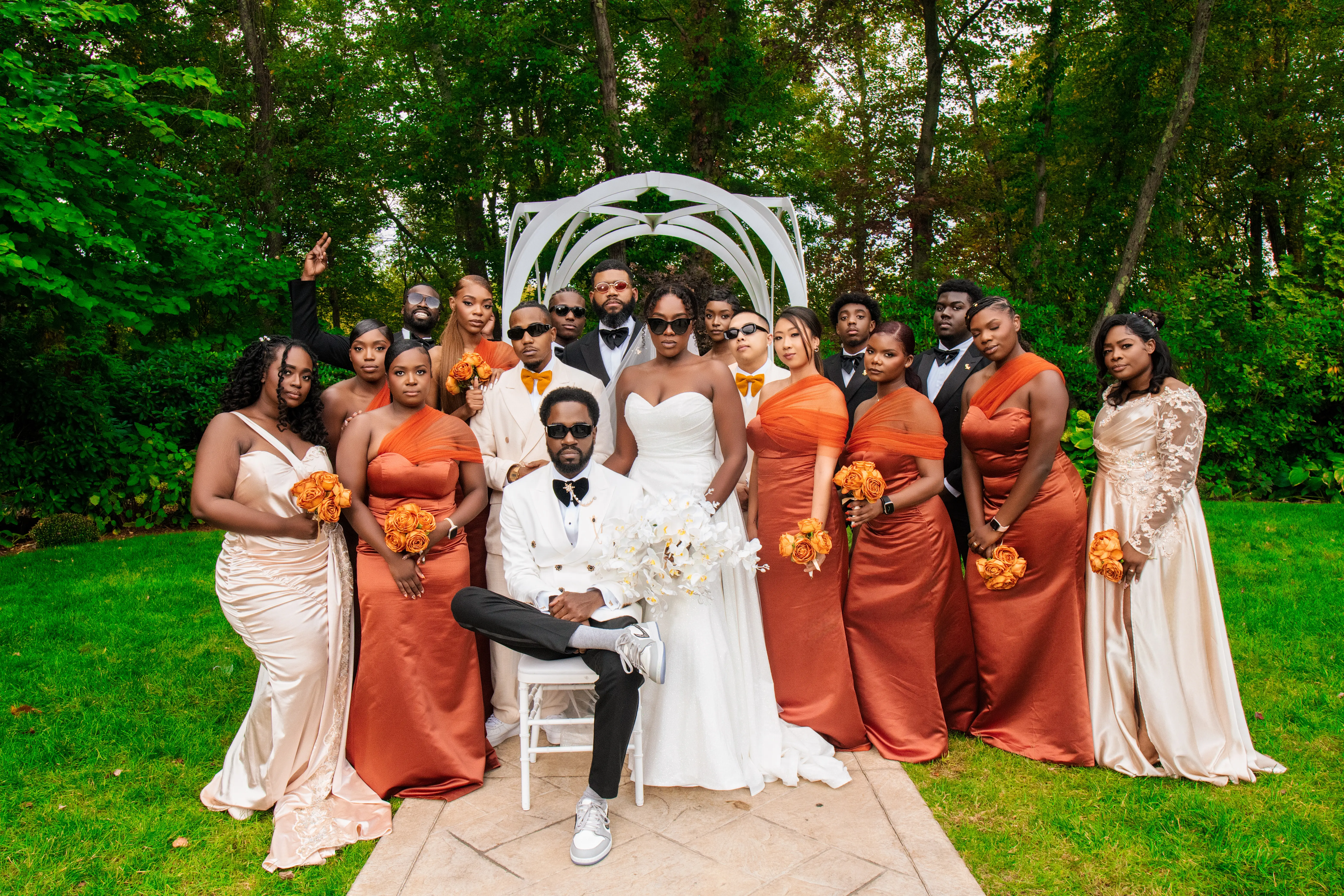 Bride Wearing Simple Fit and Flare Wedding Dress Called Anniston Lane With Bridal Party In Orange And Cream Outfits