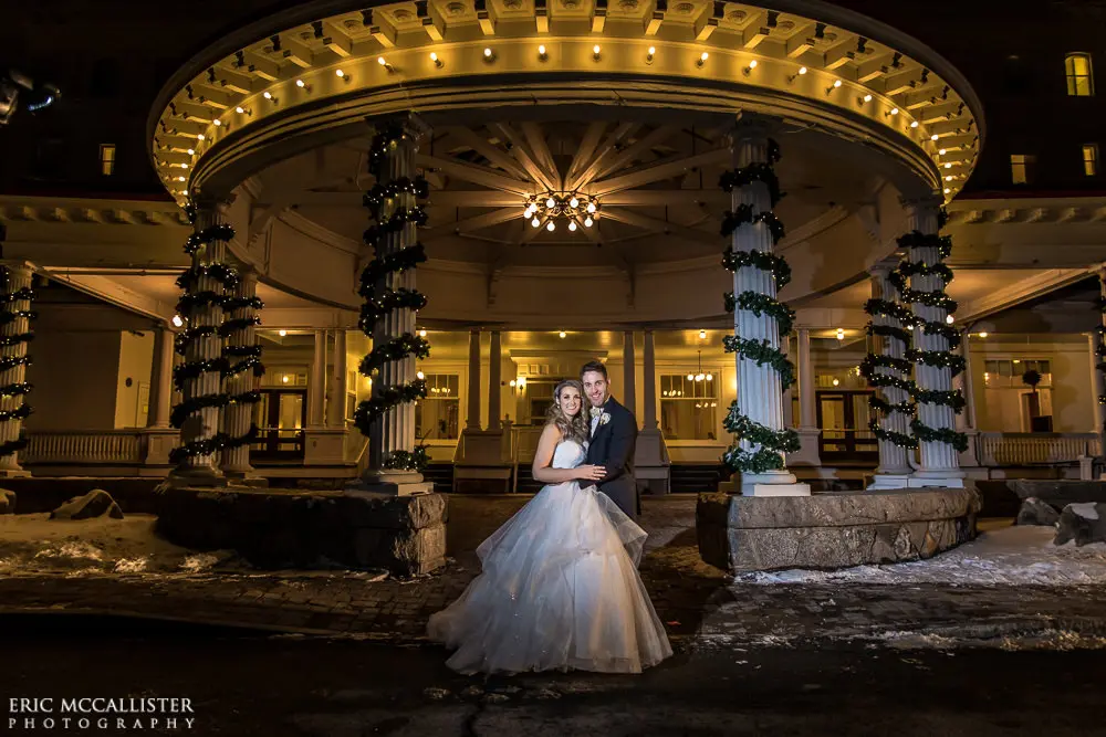 Bride with groom wearing strapless ballgown tulle wedding dress with sweetheart neckline outdoors.