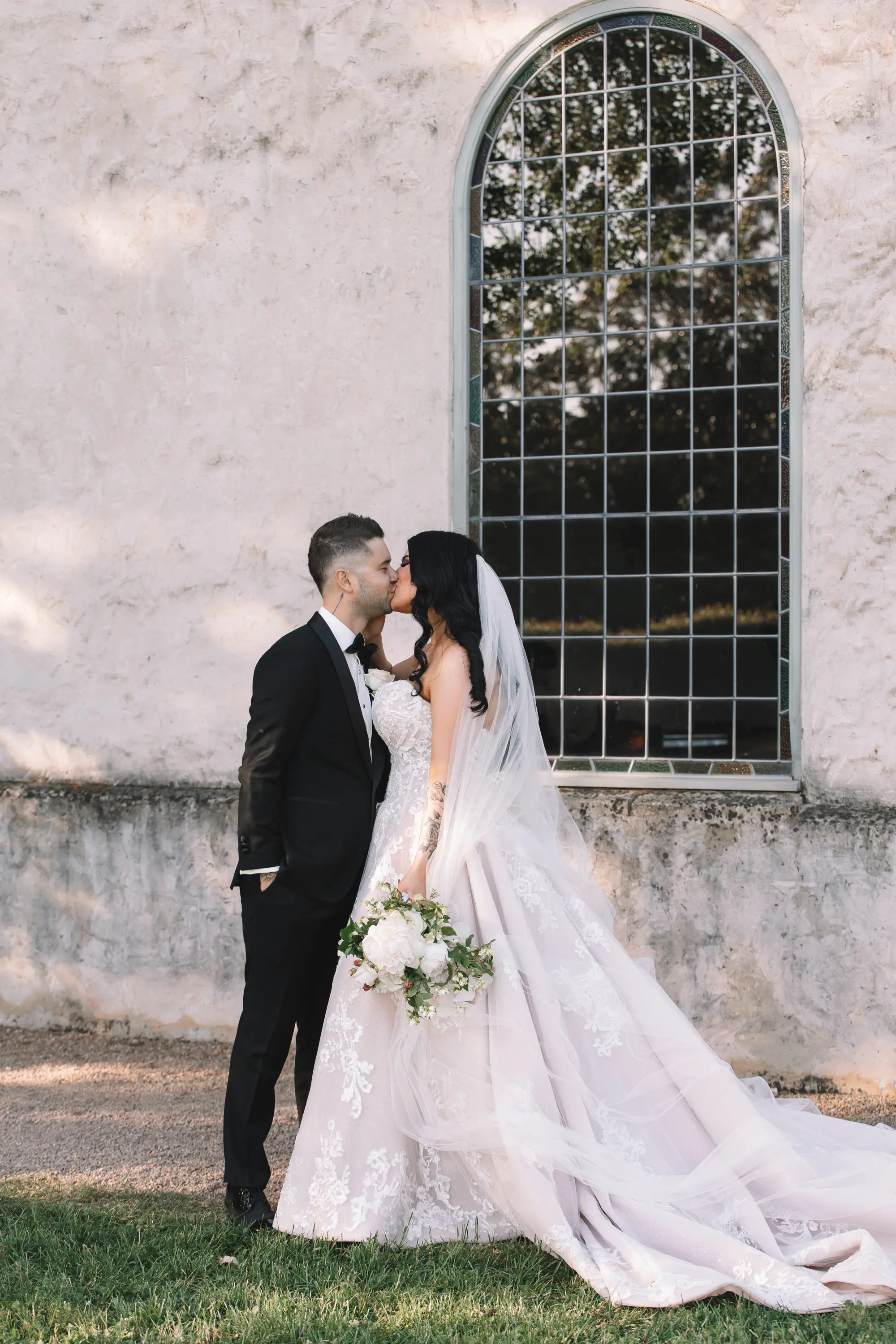Bride Wearing Princess Wedding Dress Called Norvinia By Sottero And Midgley Kissing Groom Next To A Window