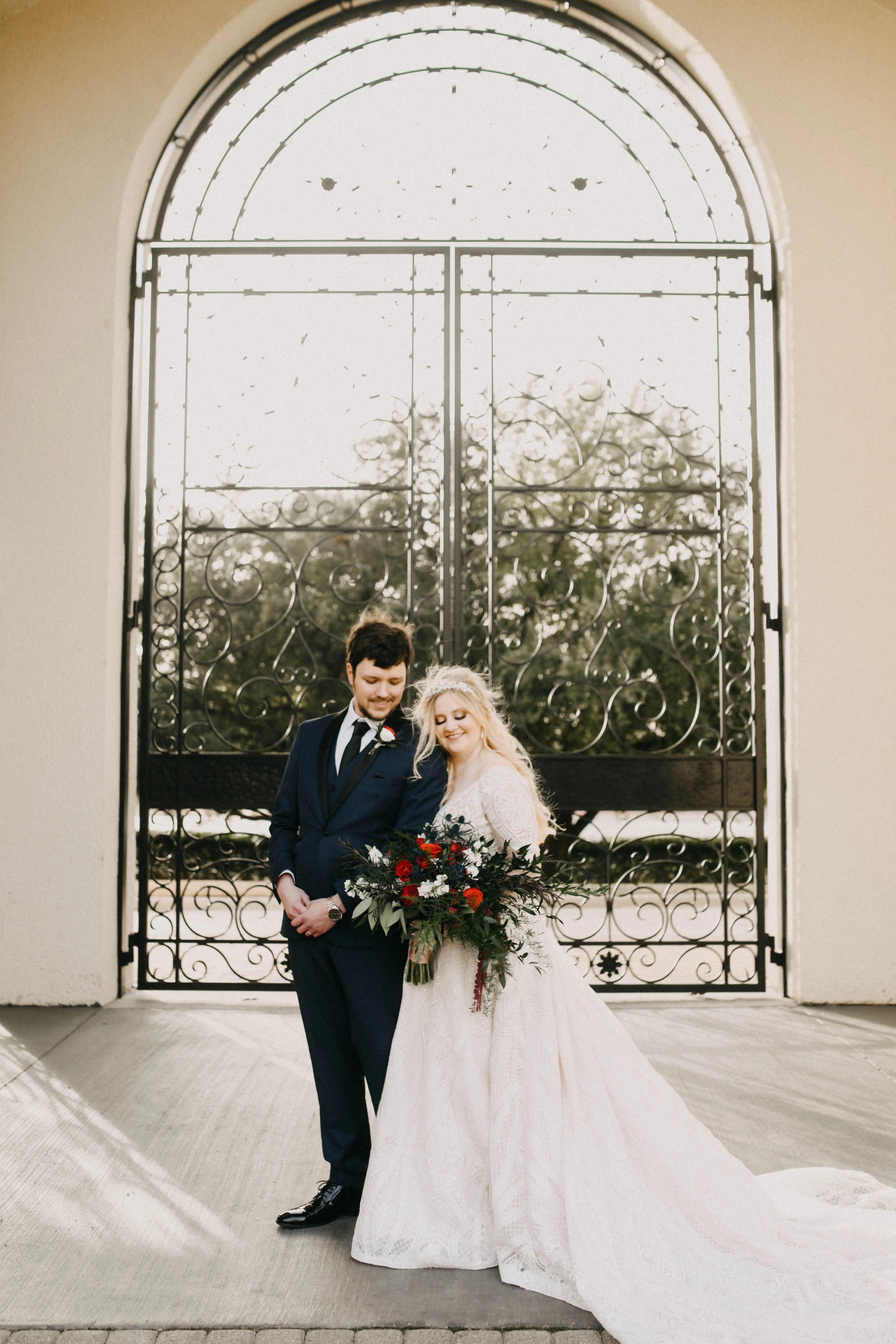 Bride and groom stood in sunlight smiling together.