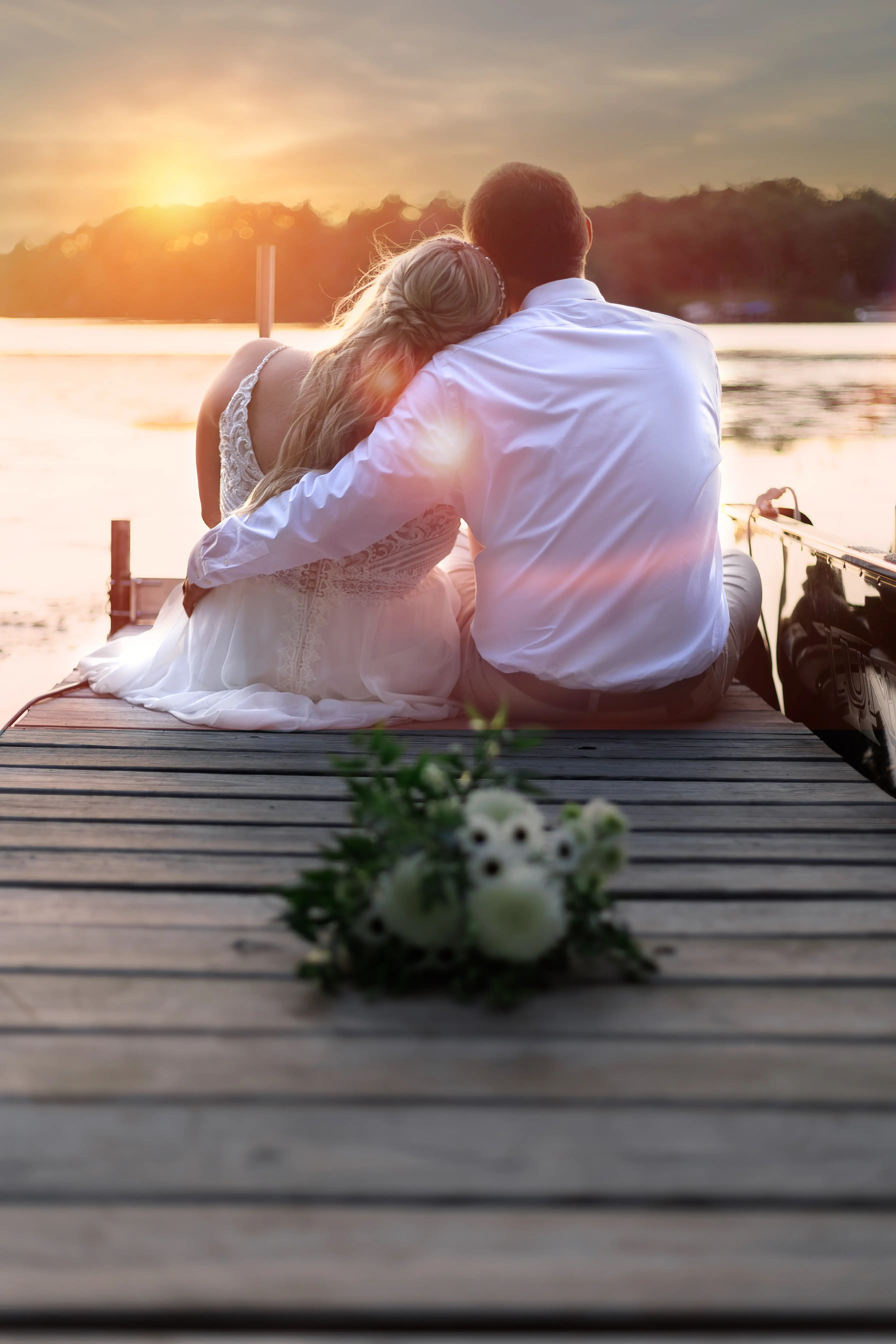 Bride Wearing Beaded Wedding Dress With Flowy Skirt Called Lorraine By Rebecca Ingram Resting Head On Groom Shoulder Looking At Water