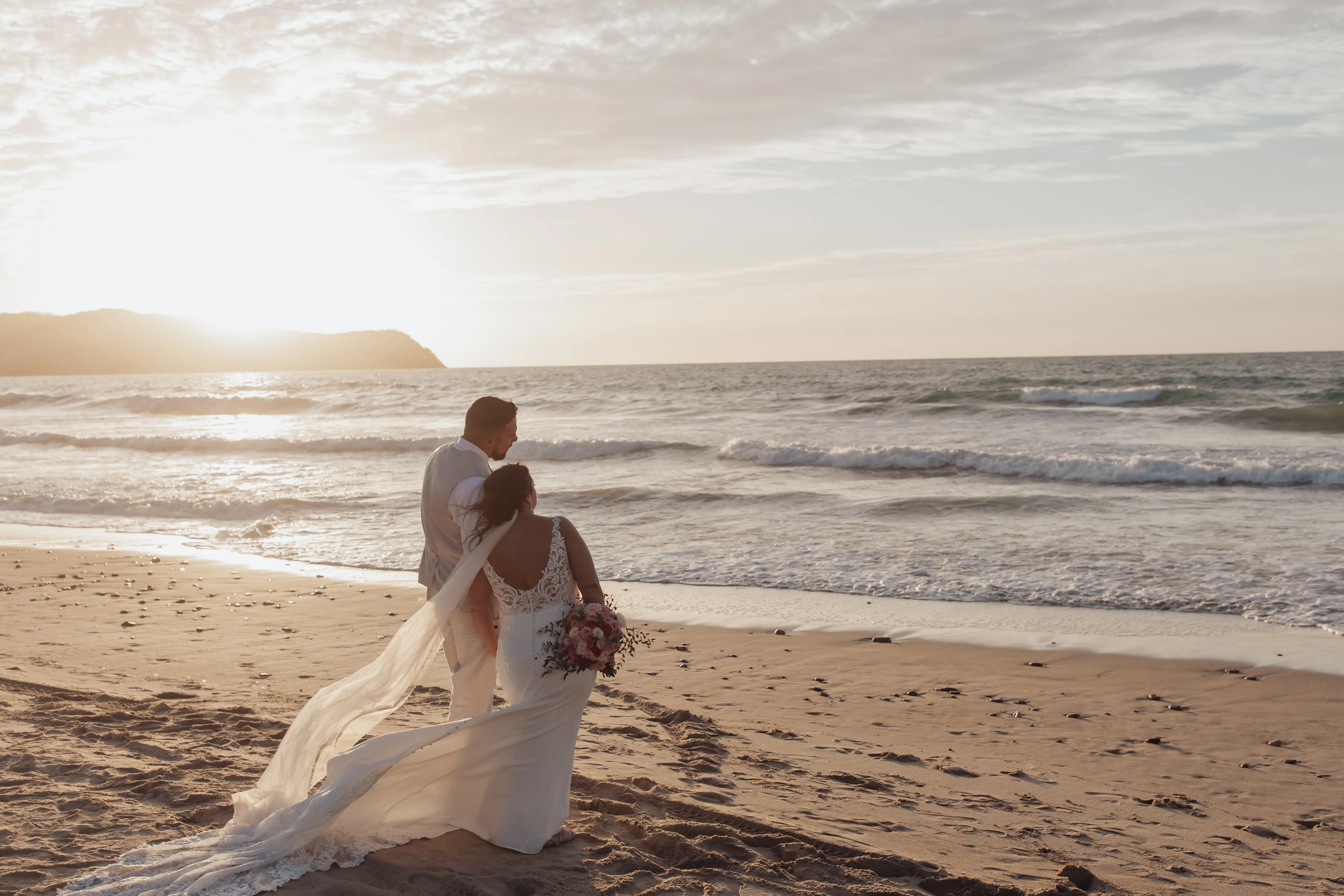Bride wearing Johanna Lane by Maggie Sottero cuddling with her husband on the beach