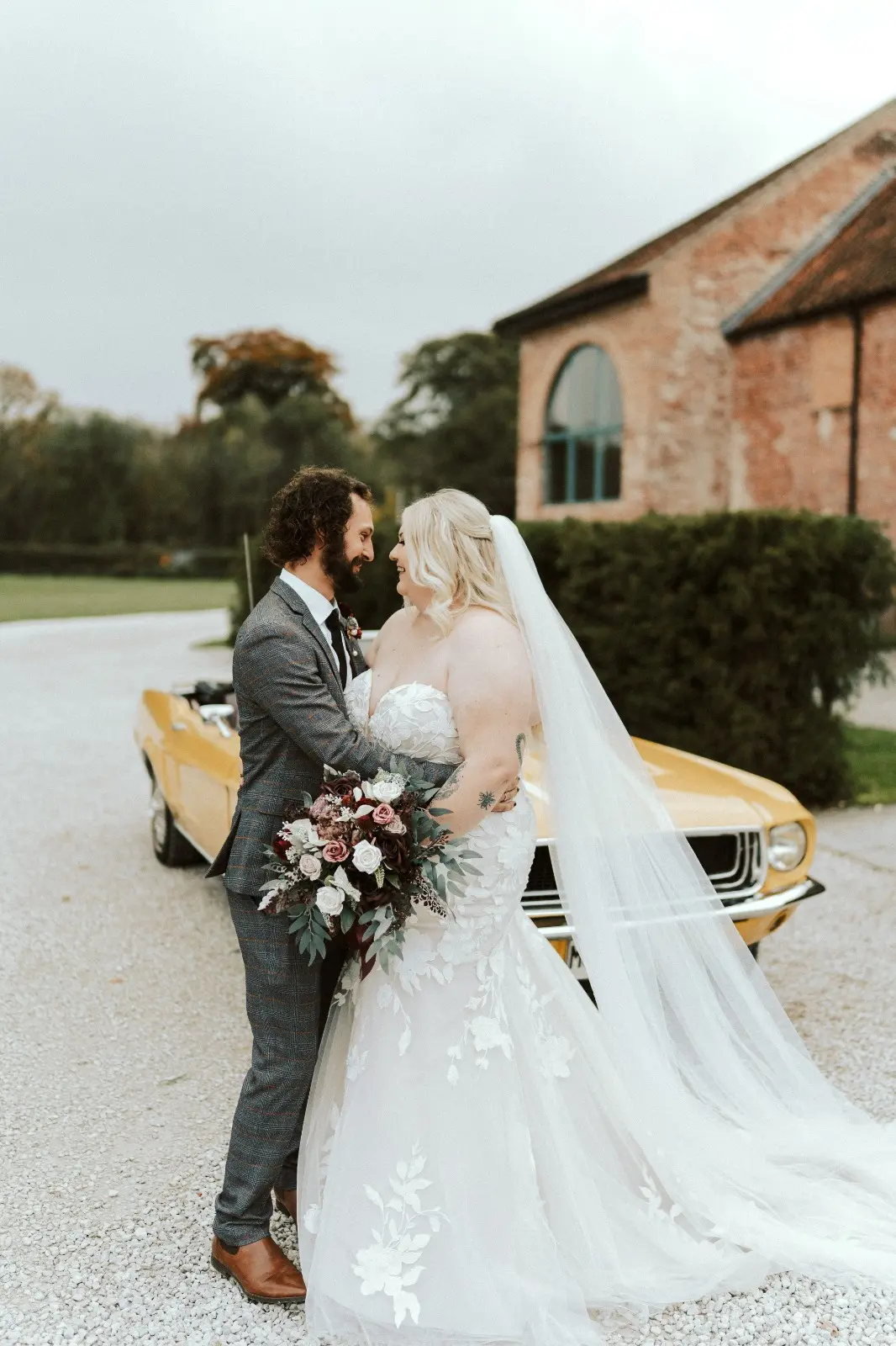 Bride Wearing Lace Mermaid Wedding Dress Called Hattie By Rebecca Ingram With Groom In Front Of Mustard Colored Car