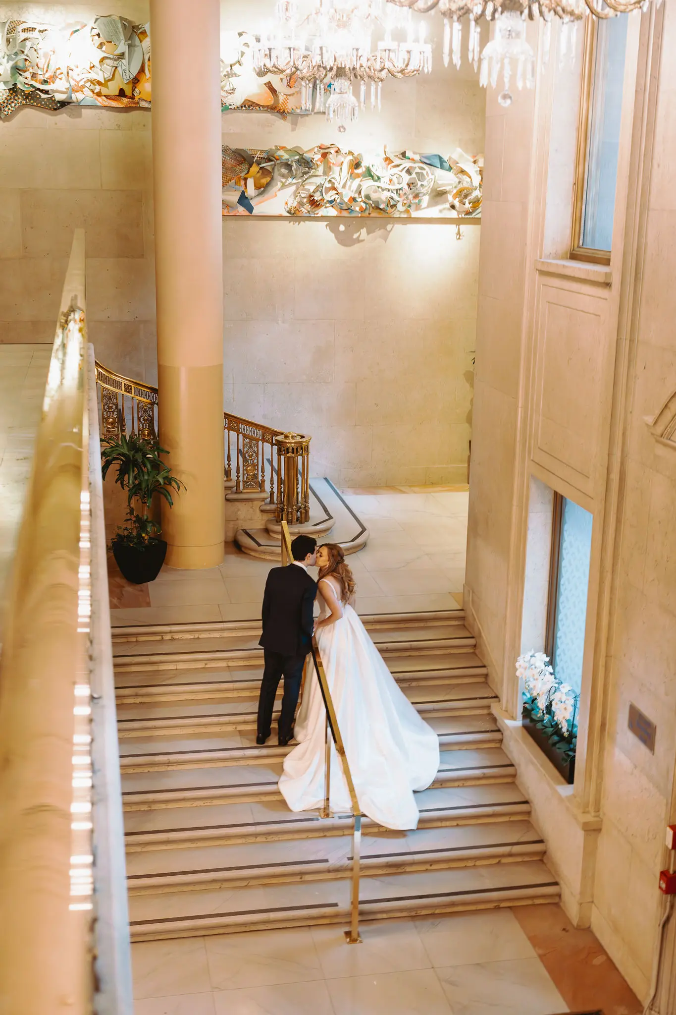 Bride wearing Selena wedding gown by Maggie Sottero kissing her husband on the stairs
