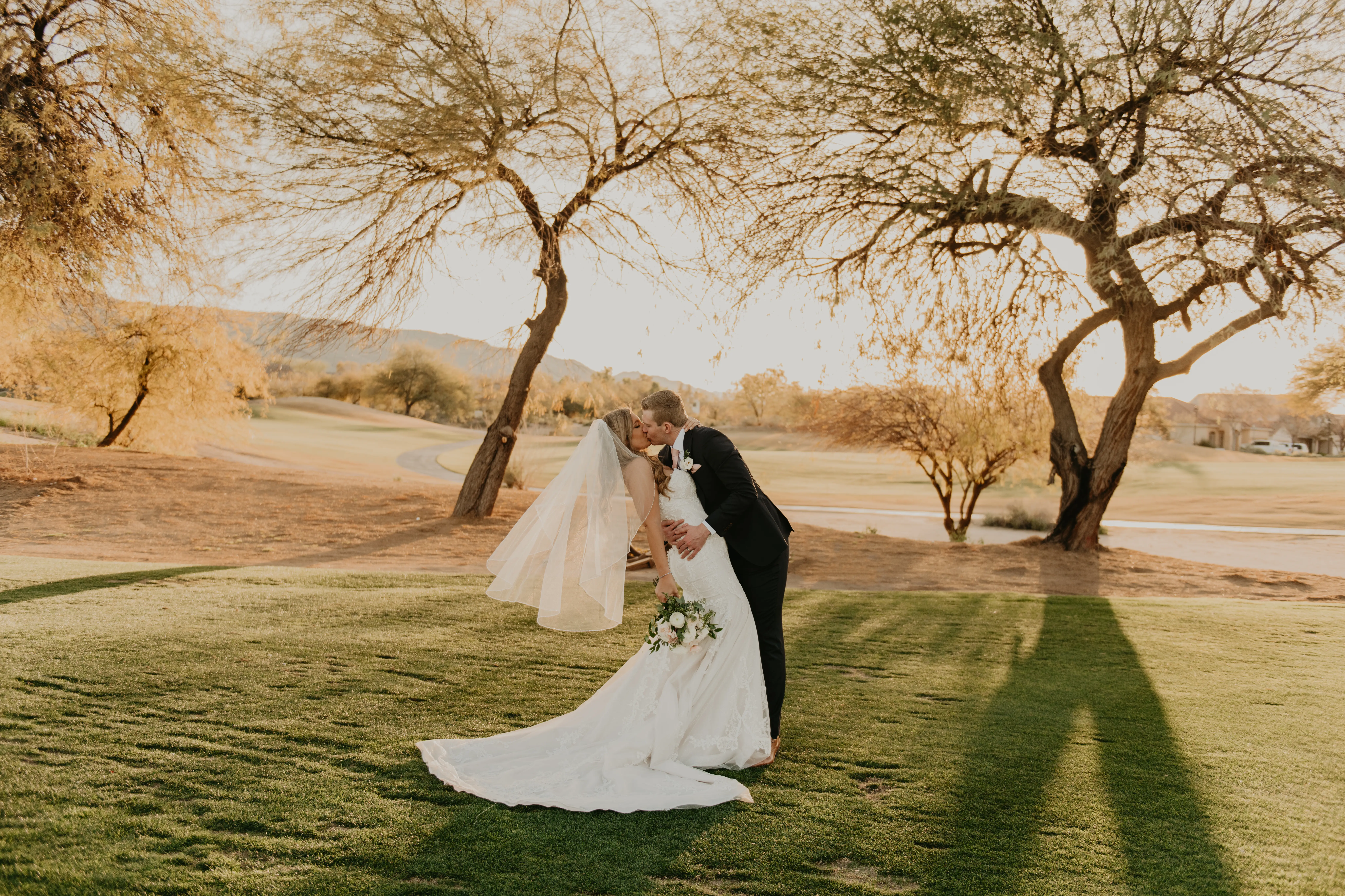 Groom Kisses Bride Wearing Elegant Mermaid Dress Fredrique by Maggie Sottero