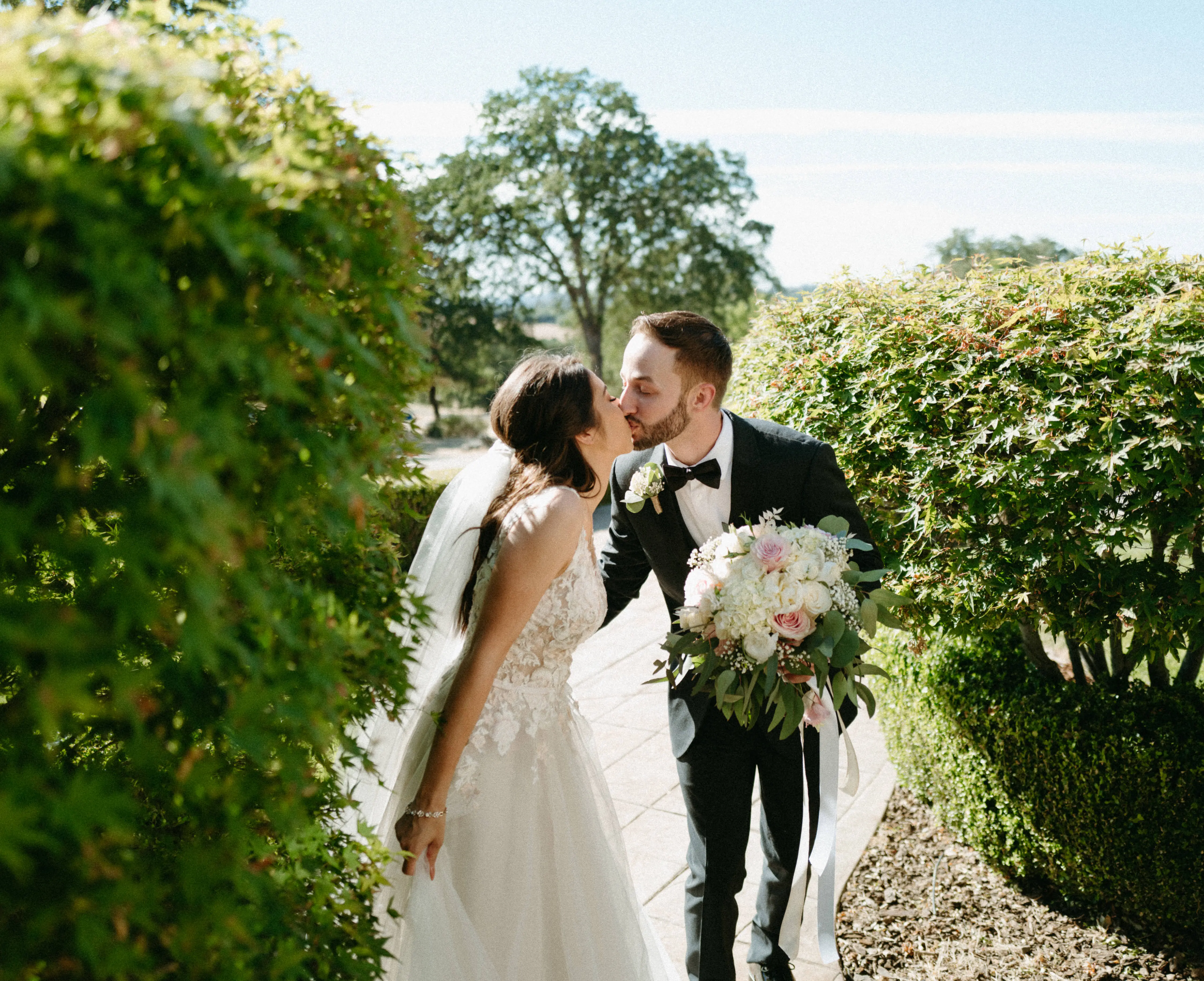 Groom Kissing Bride in Magical A-Line Wedding Dress with Textured Illusion Motifs Called Minerva by Rebecca Ingram