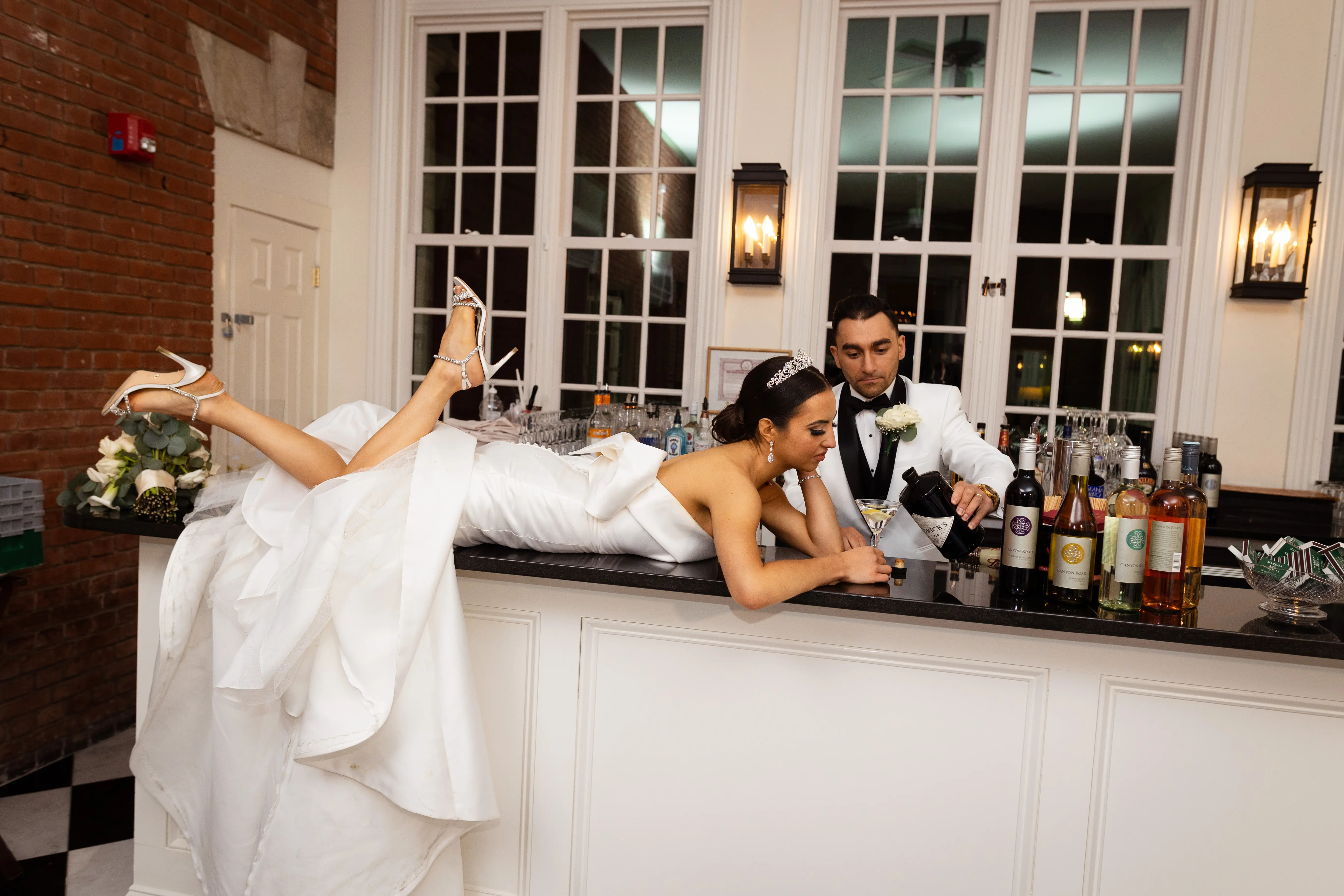 Bride And Groom Making Drinks. Bride Wearing Unique Strapless Wedding Gown With Statement Bow Called Mitchell By Maggie Sottero