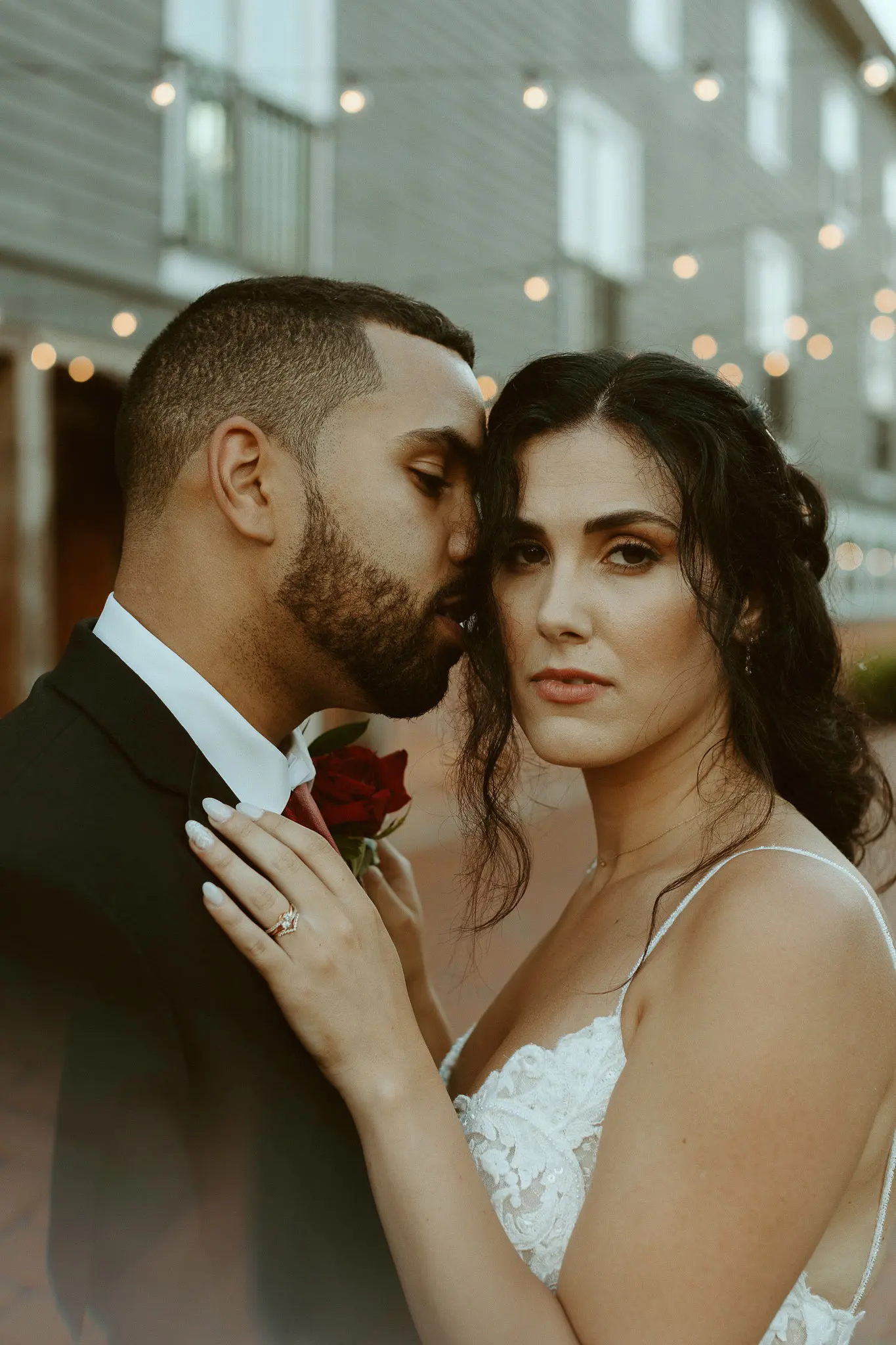 Bride with groom wearing lace sheath wedding dress.