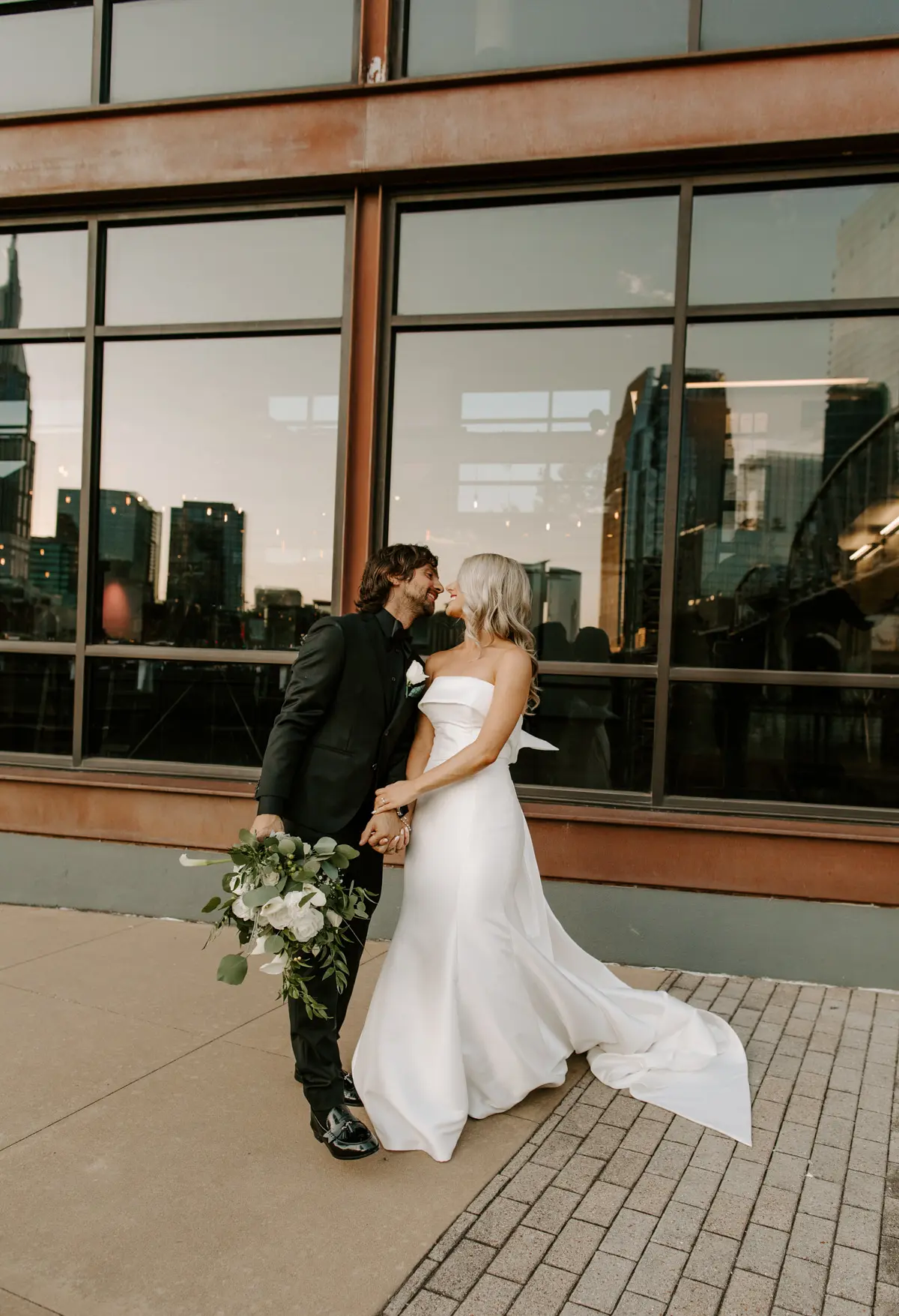 Groom With Bride Wearing Unique Strapless Wedding Dress With Beautiful Back Bow Mitchell By Maggie Sottero