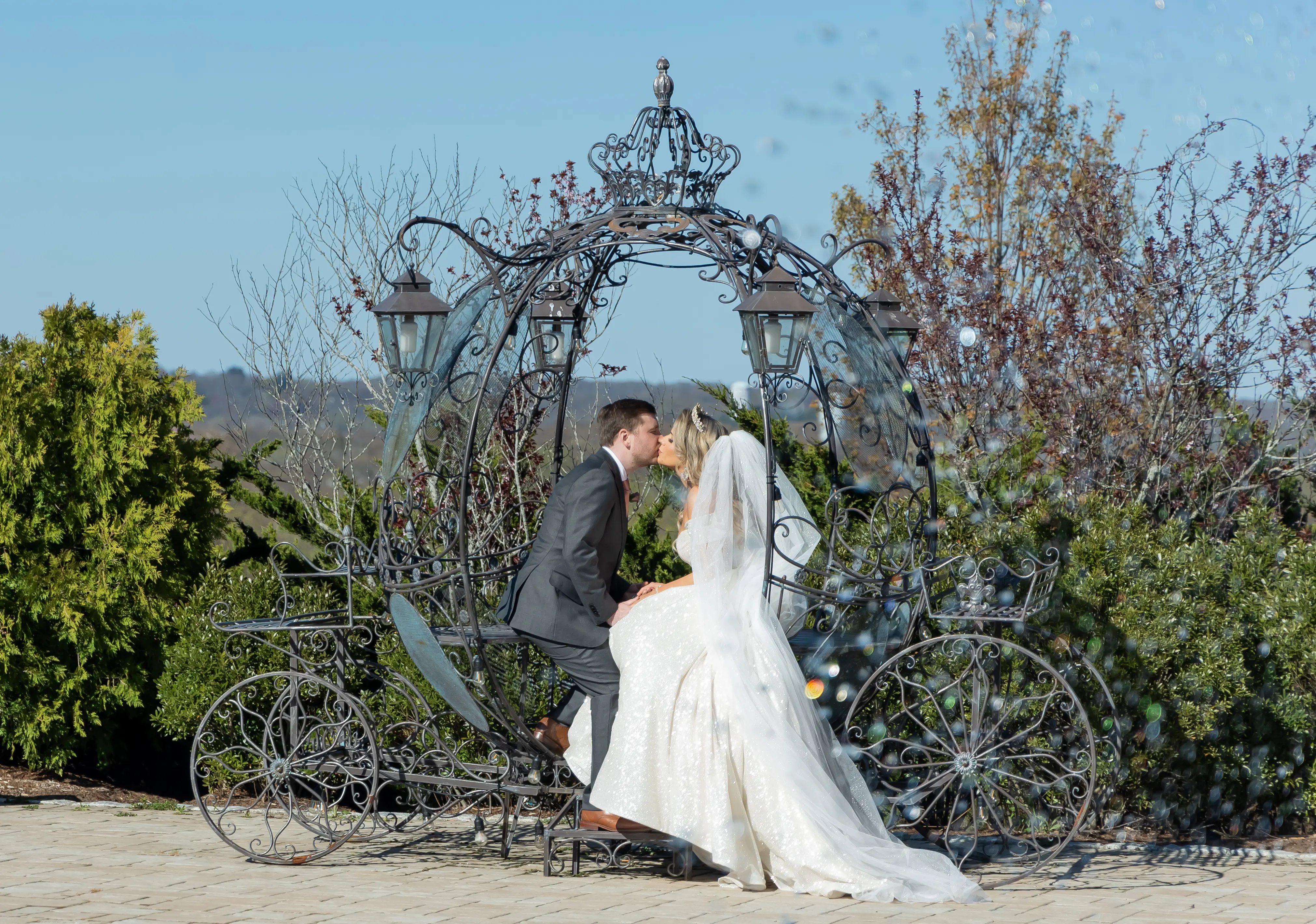 Bride wearing Anniston by Maggie Sottero taking a carriage ride with her husband