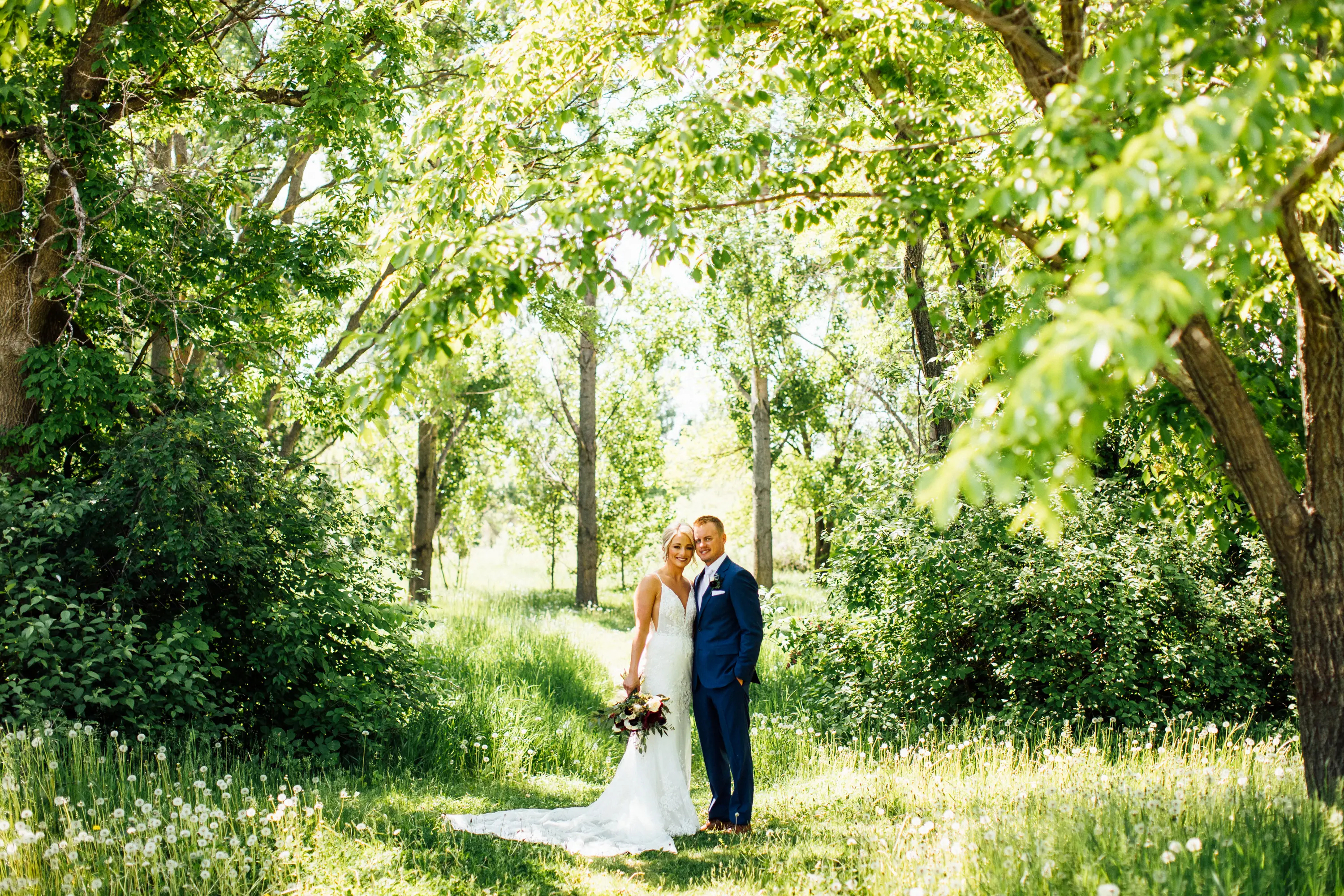 Bride Wearing Graceful Sparkly Lace Wedding Dress Called Fontaine By Maggie Sottero Standing With Groom Surrounded By Trees