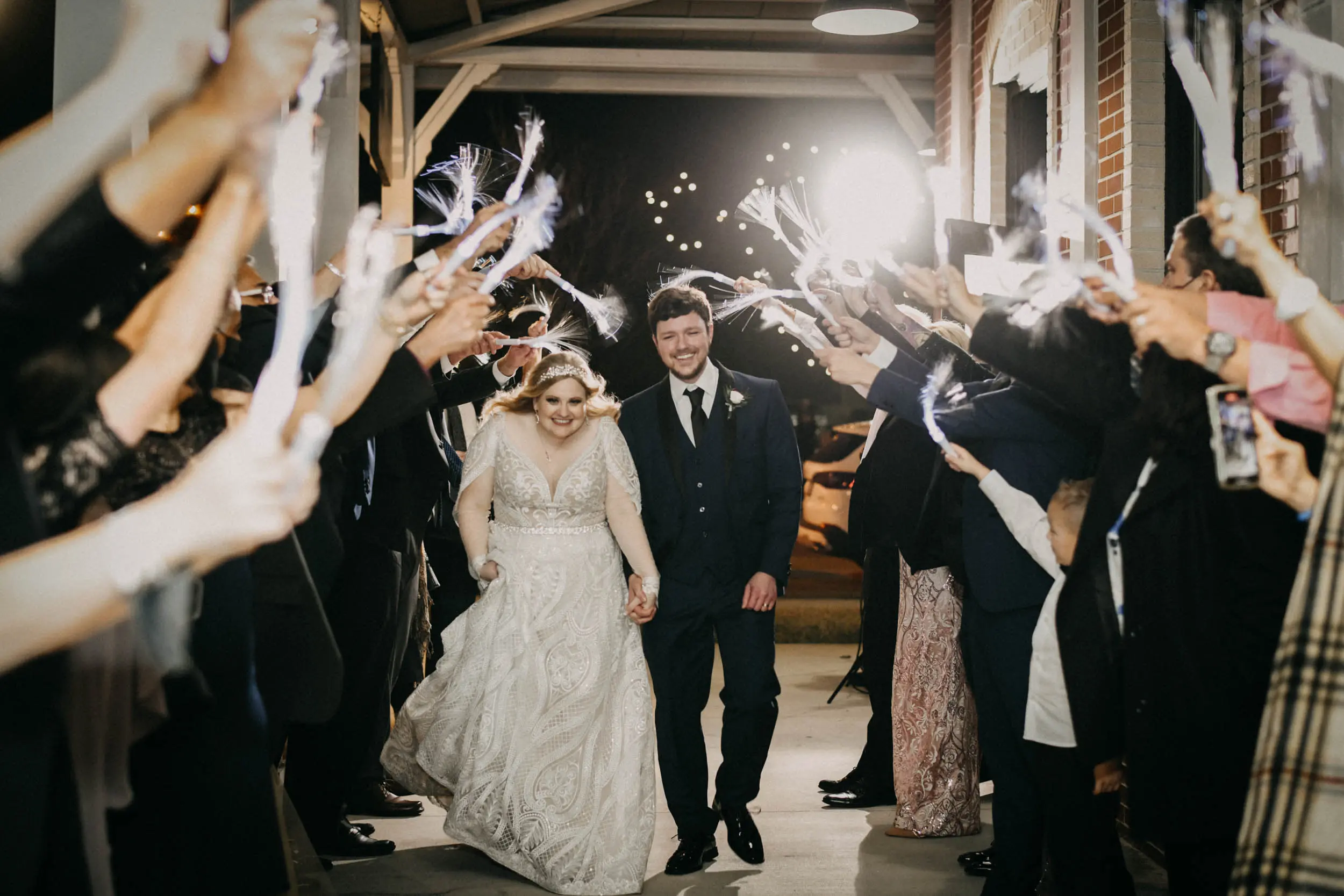Bride and groom leaving their wedding with wedding party waving lights and celebrating!