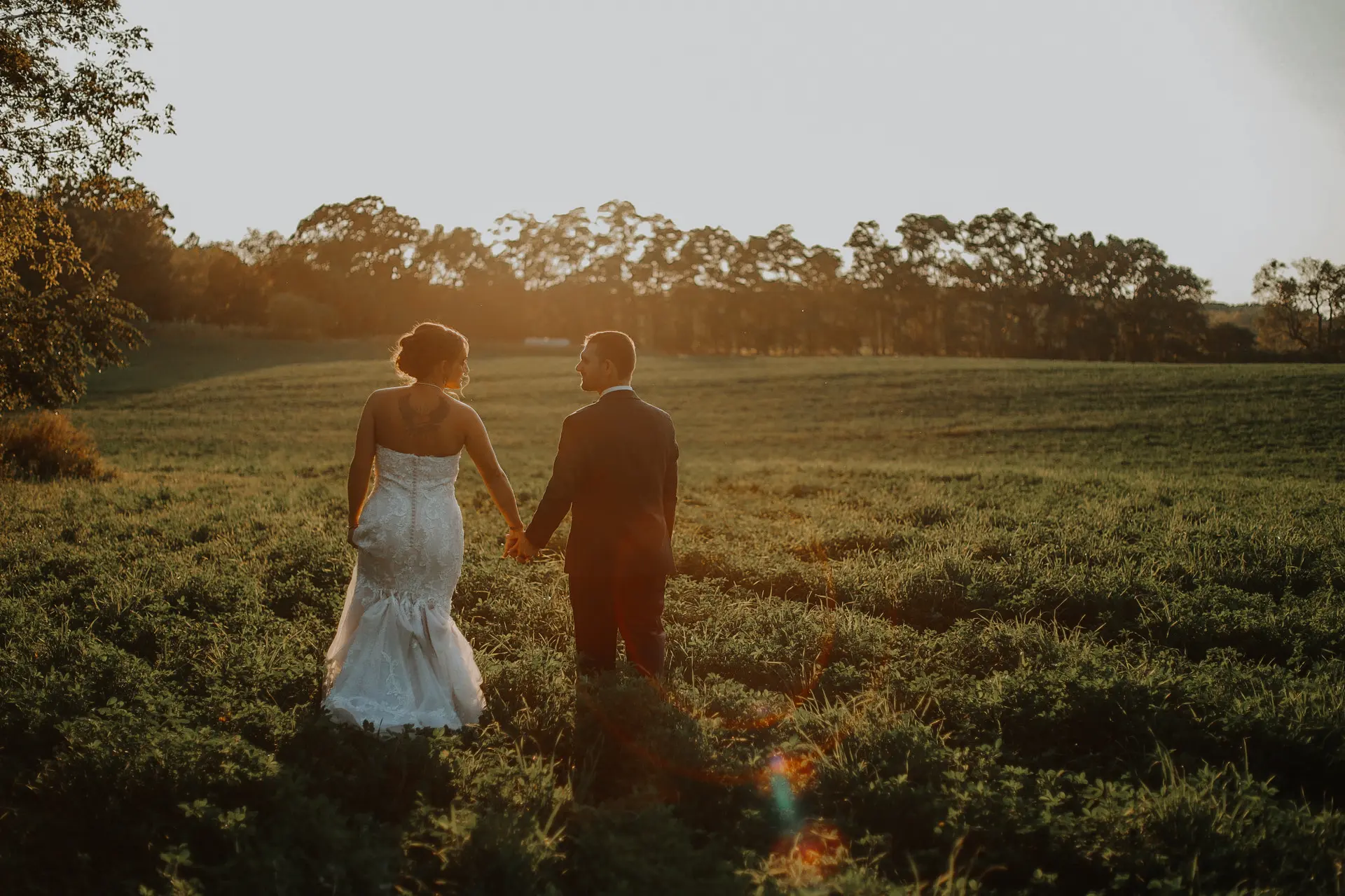 Bride wearing Marguerite wedding dress by Maggie Sottero holding hands with her husband