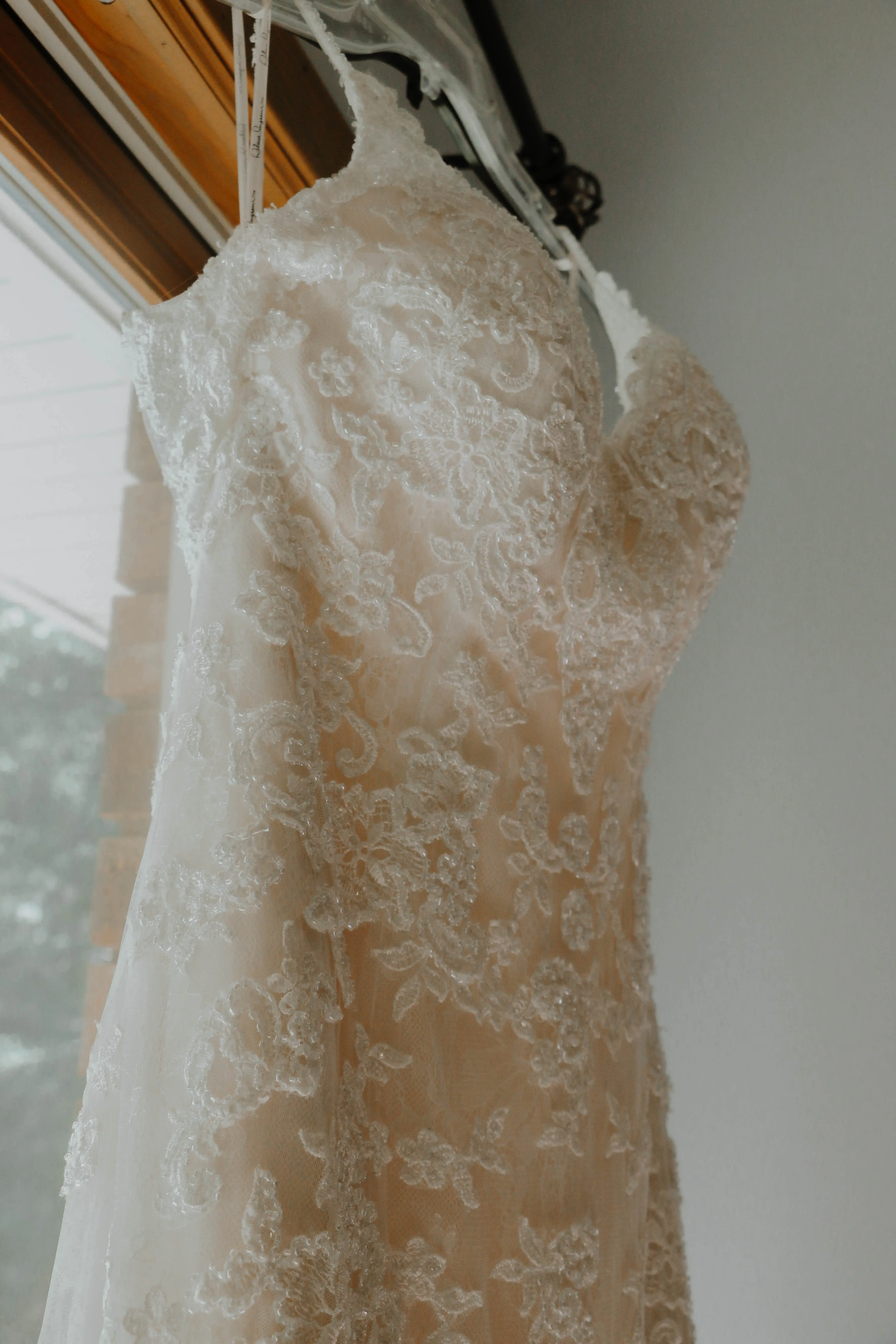 Close up of lace detail of wedding dress with daylight shining on it.
