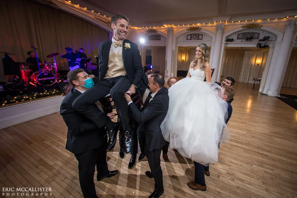 Bride dancing with groom wearing strapless ballgown tulle wedding dress with sweetheart neckline indoors on dance floor.
