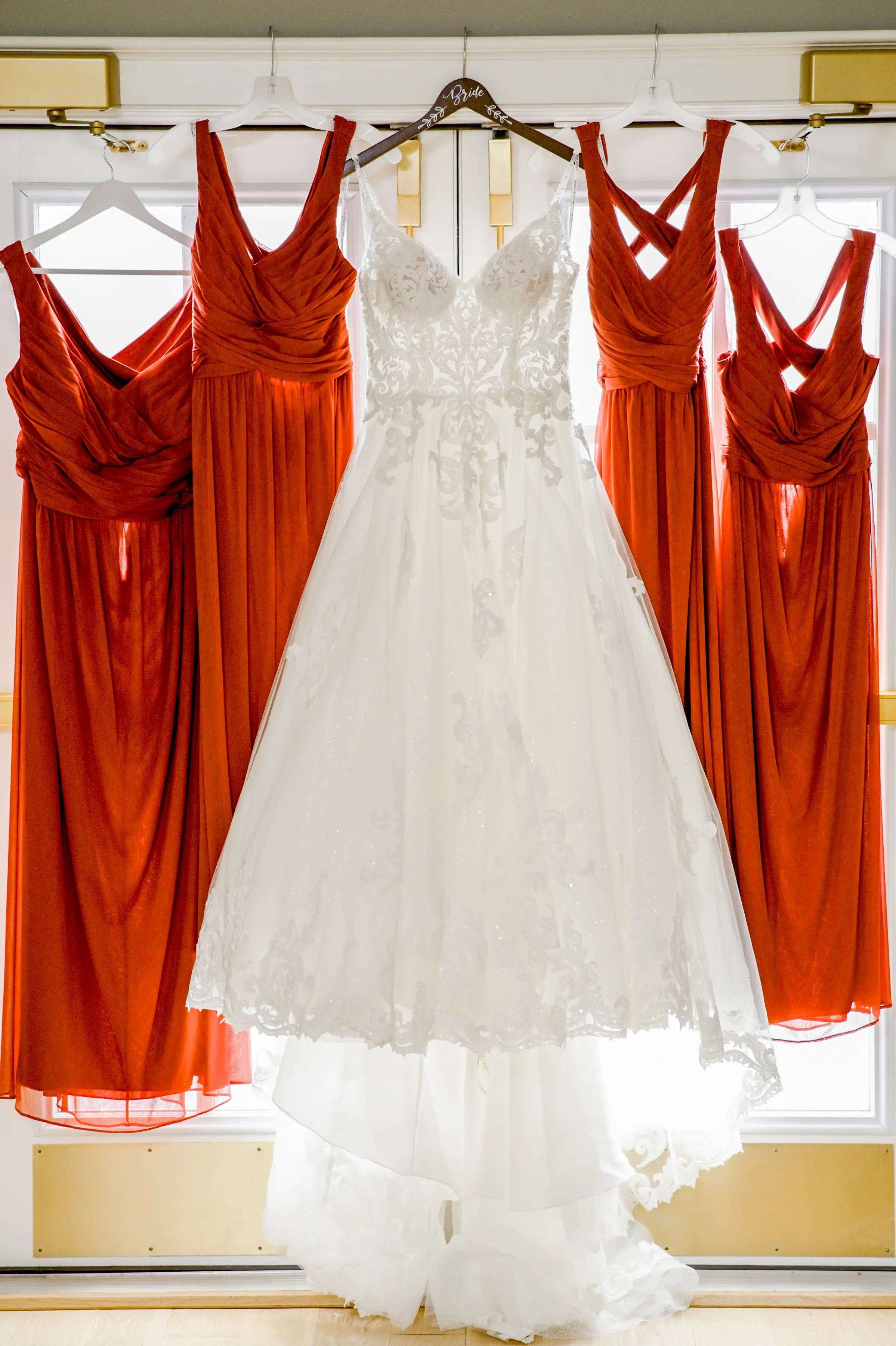 Florence wedding dress by Maggie Sottero hanging up next to bridesmaid dresses