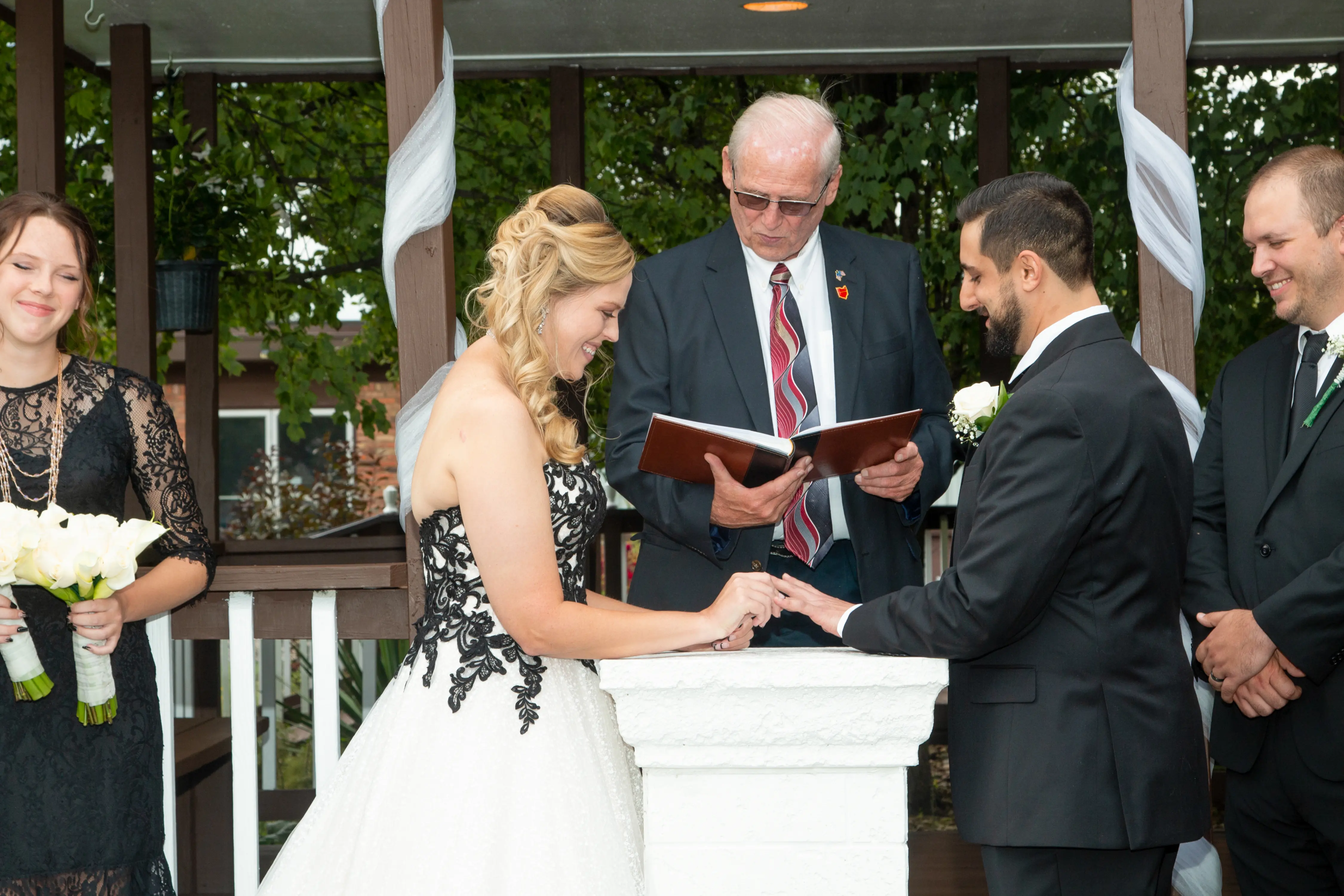 Bride Wearing A-Line Black Lace Wedding Dress Called Tristyn By Maggie Sottero Exchanging Rings With The Groom