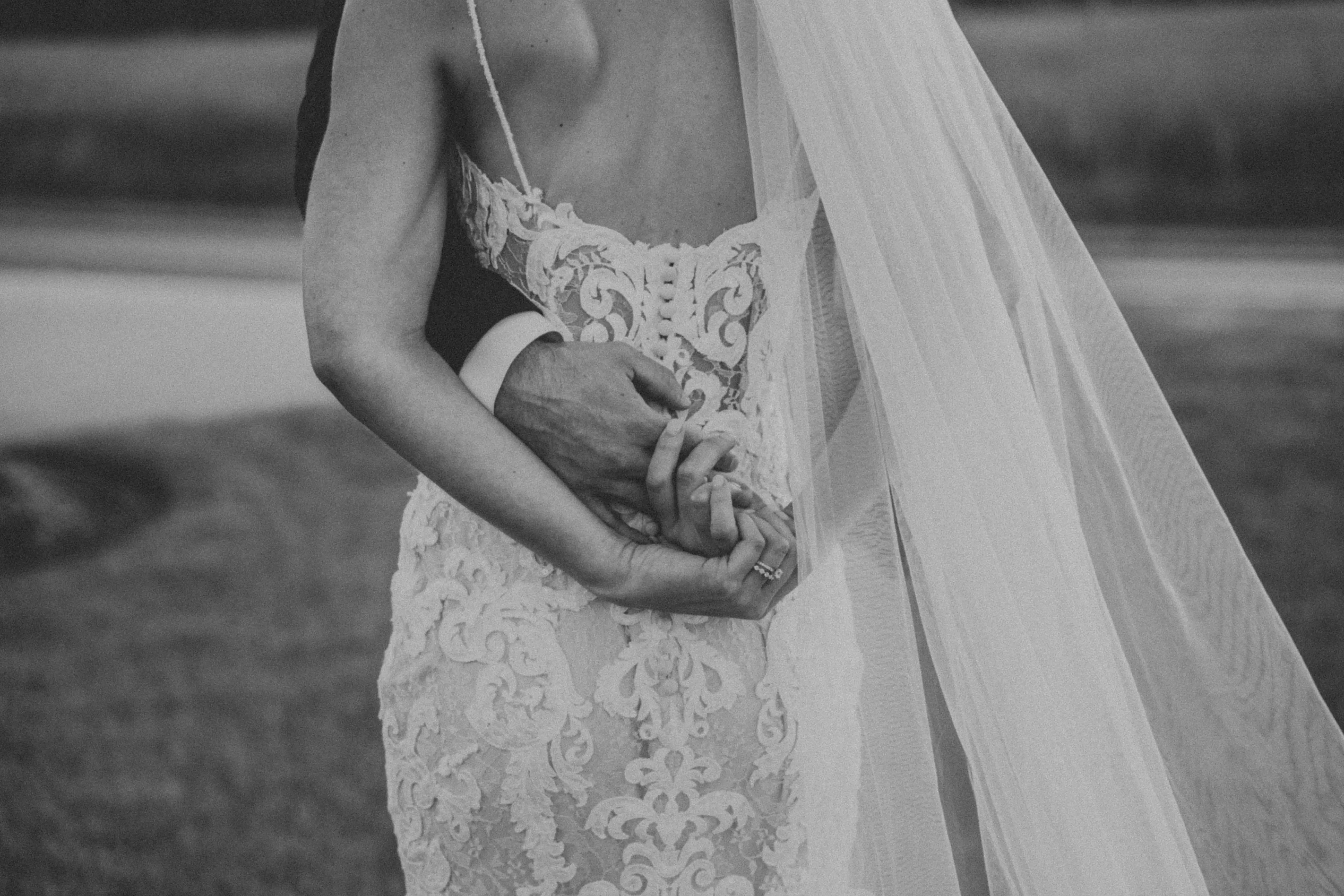 Groom Embraced with Bride in Mermaid Wedding Dress with Shimmering Lace Motifs and Illusion Plunging Sweetheart Neckline Called Tuscany by Maggie Sottero