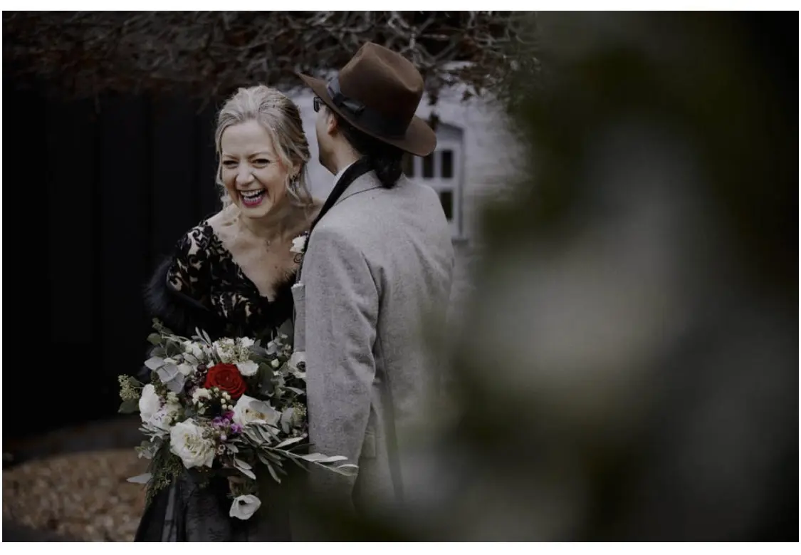 Bride Wearing Black Lace Wedding Gown Called Zander By Sottero and Midgley Laughing At Something The Groom Said