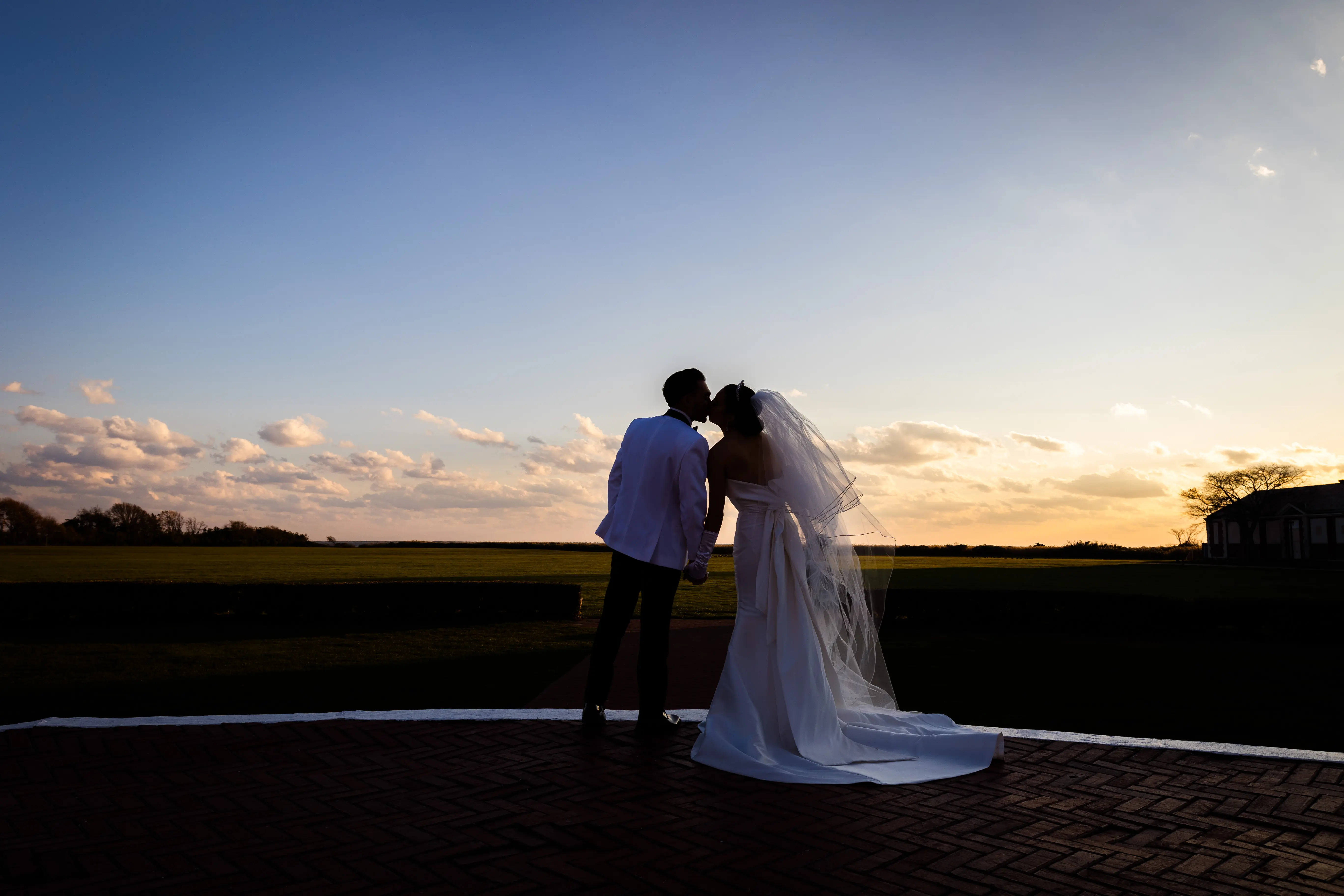 Bride And Groom Share Kiss. Bride Wearing Unique Strapless Wedding Gown With Statement Bow Called Mitchell By Maggie Sottero