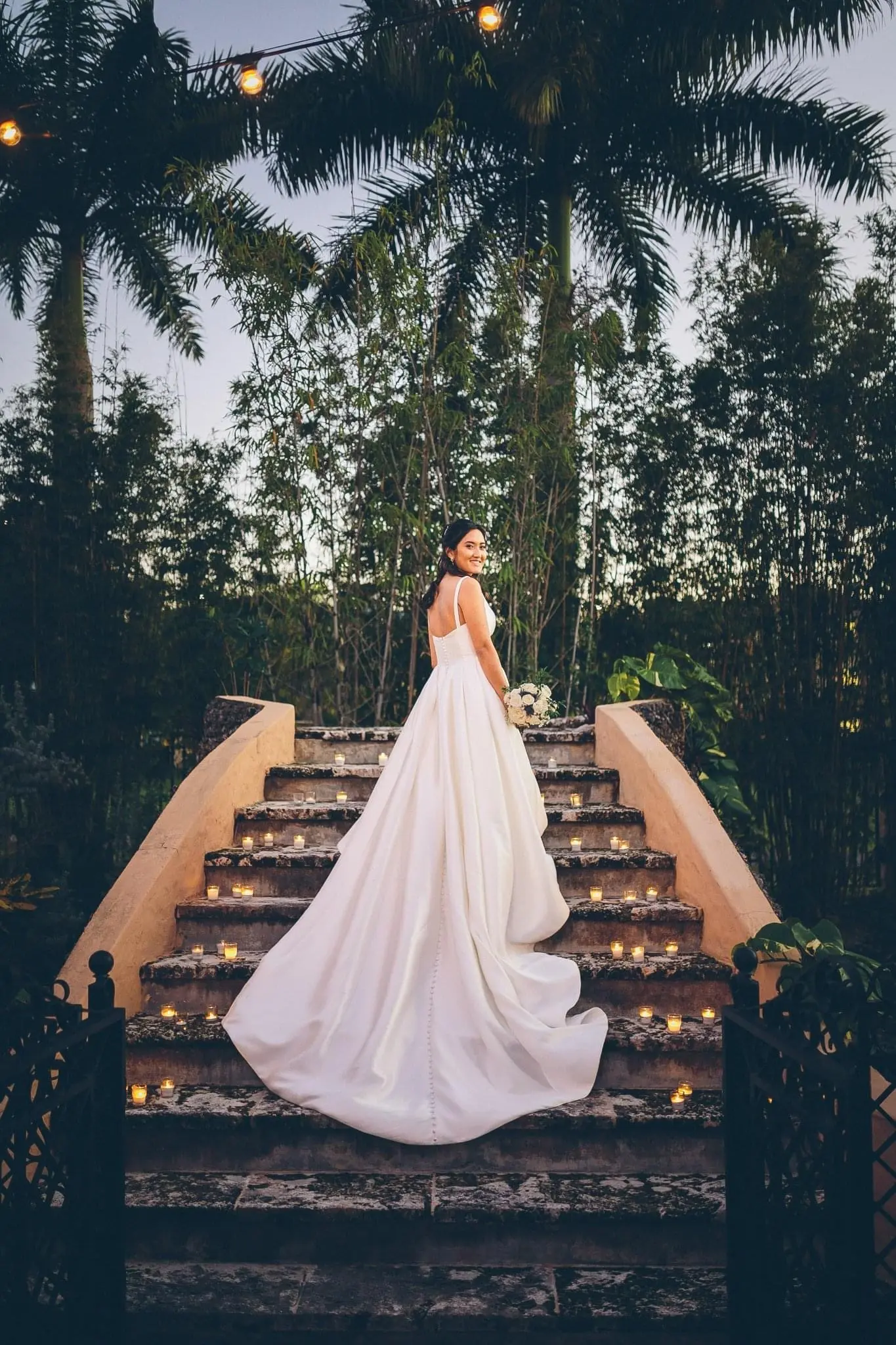 Bride Posing on Stairs With Bouquet And Candles In Shiny Ball Gown Wedding Dress Called Selena By Maggie Sottero