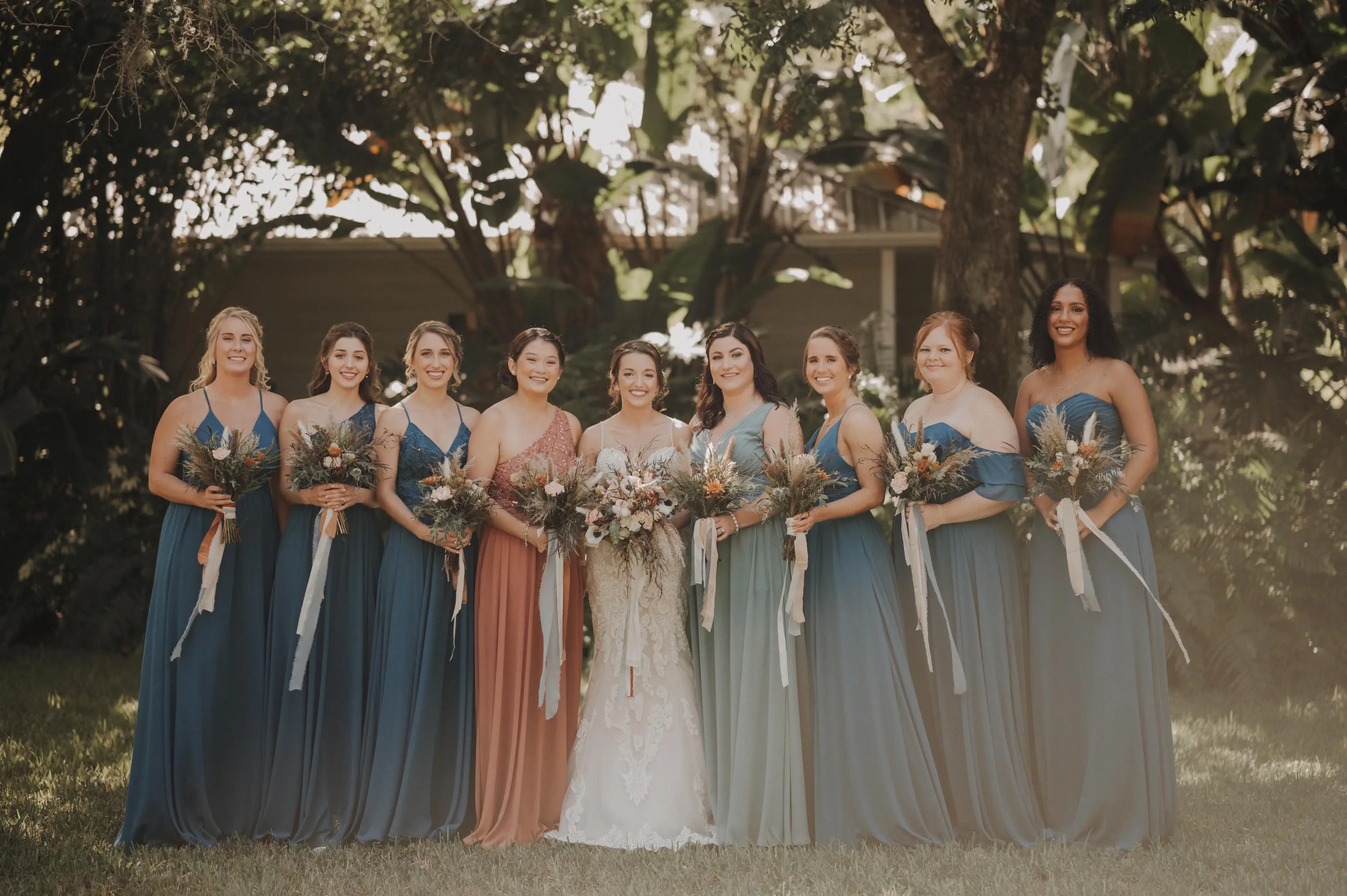 Bridemaids in teal full length gowns and MOH wearing a rust full length gown with Bride Wearing Lace Mermaid Wedding Gown Called Fiona by Maggie Sottero
