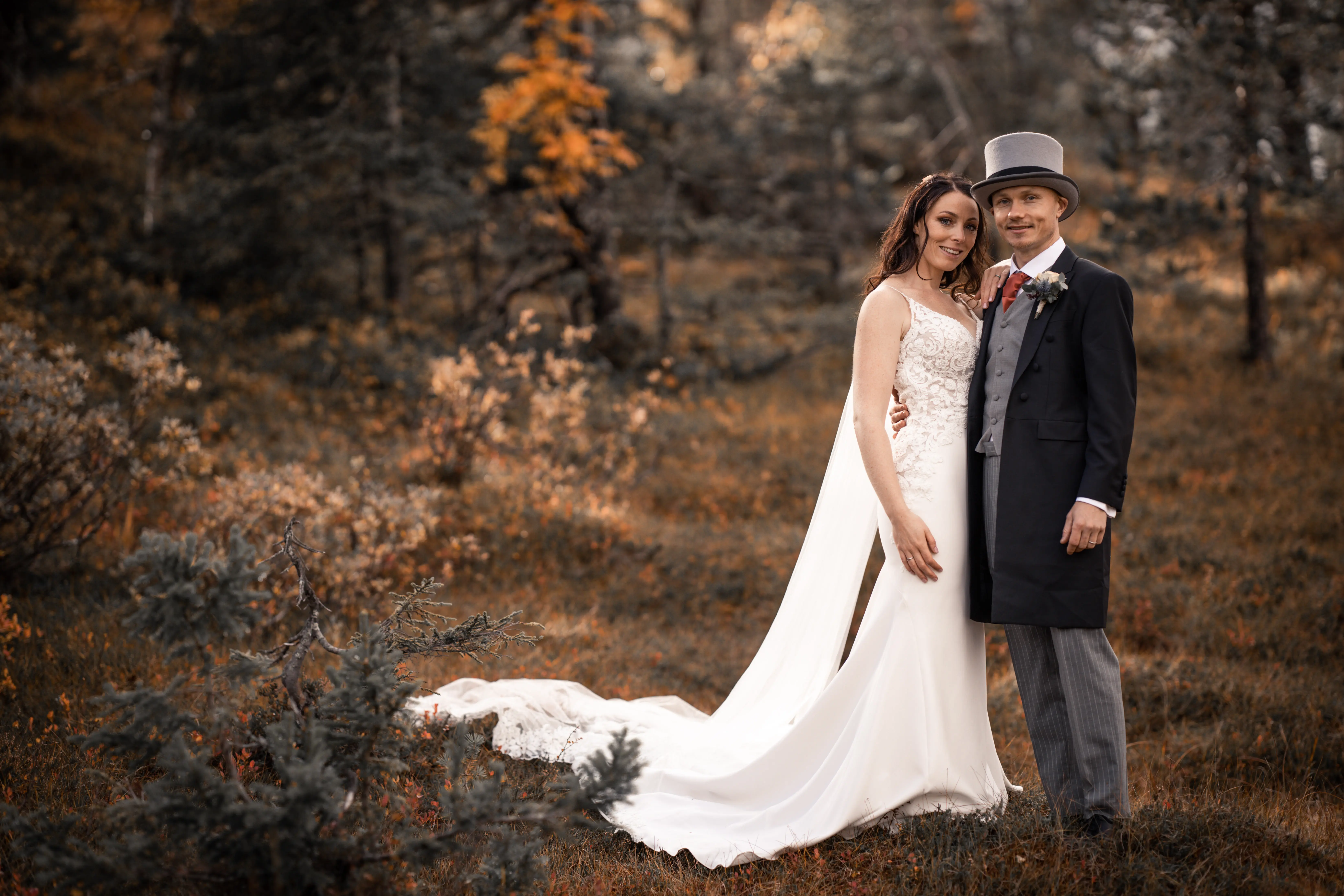 Bride wearing wedding dress called Nikki stood with her groom in grey and rust colors.