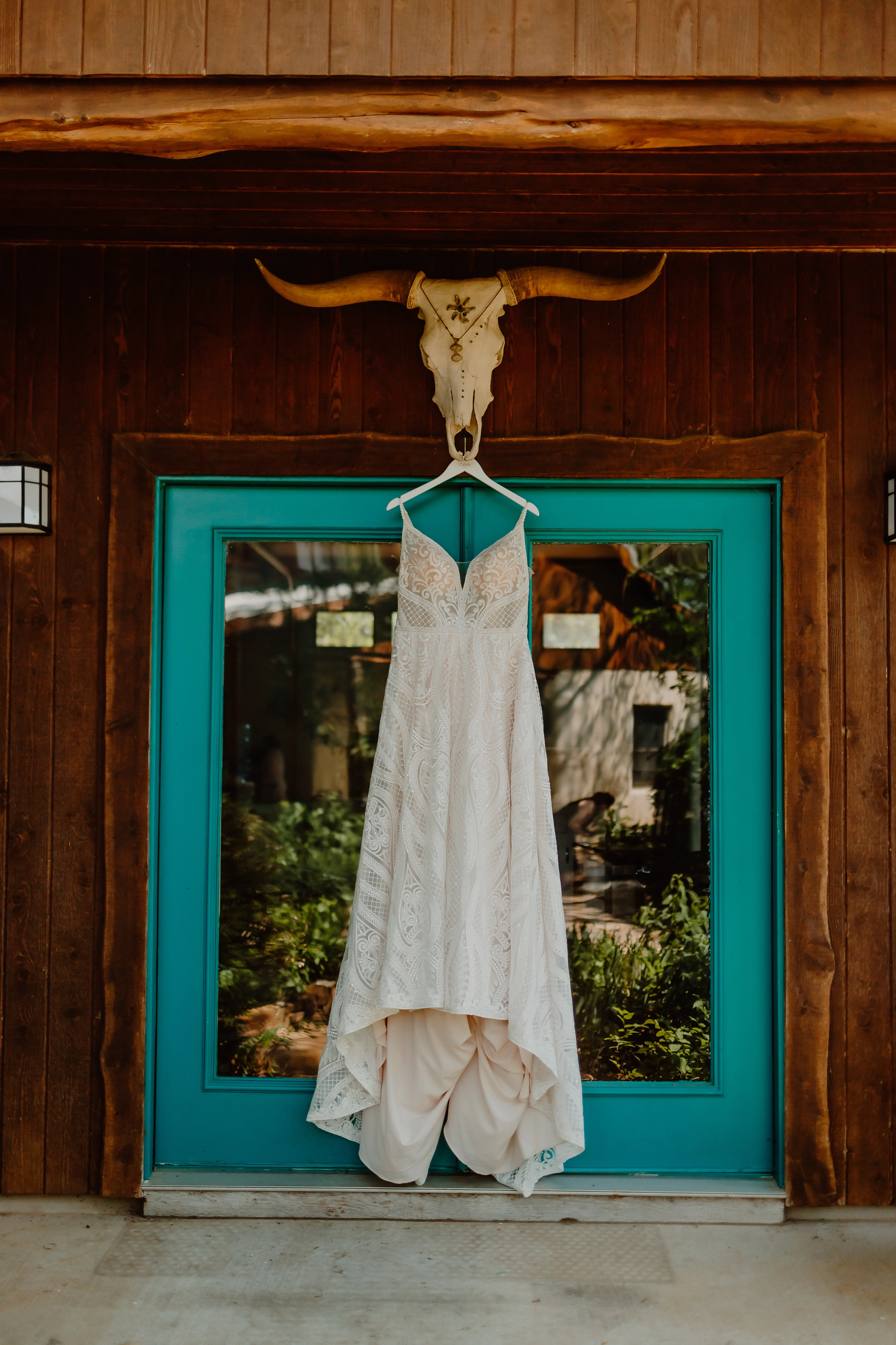 White Lacey A Line Spaghetti Strap Wedding Dress Called Roxanne By Sottero And Midgley On A Hanger In Front Of Blue Door