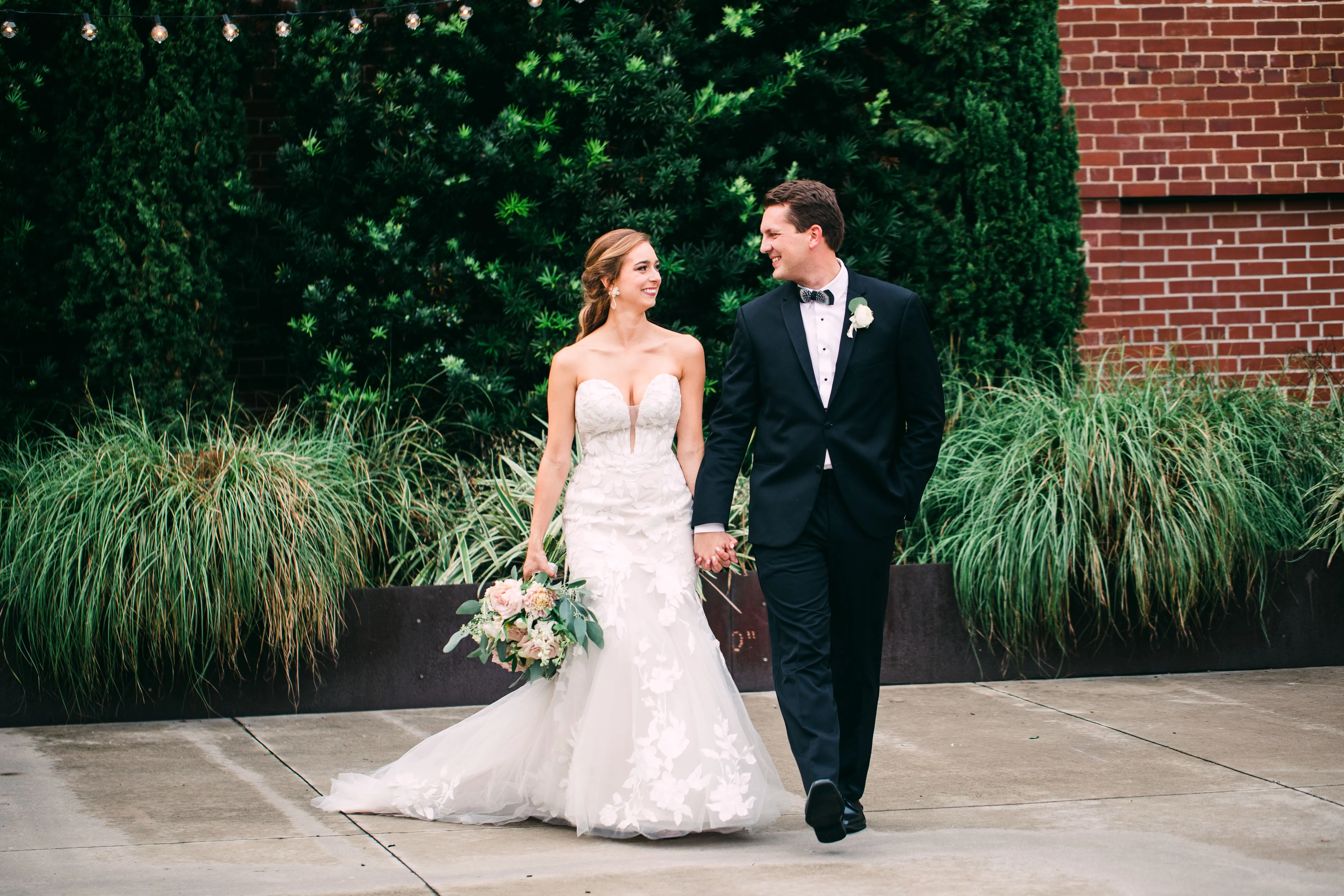 Bride with groom wearing strapless mermaid wedding dress with oversized lace