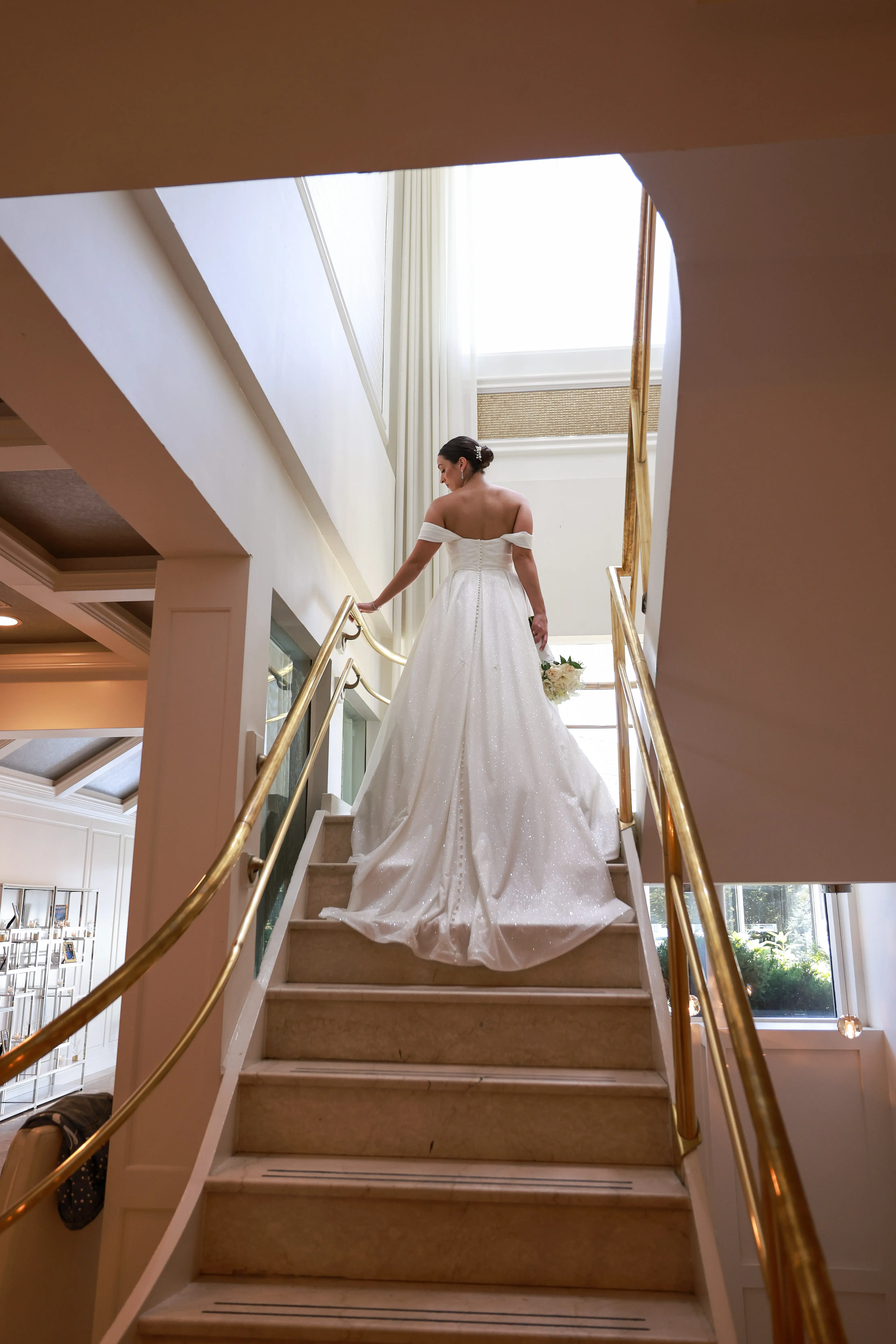 Bride wearing Anniston wedding dress by Sottero and Midgley walking up the stairs