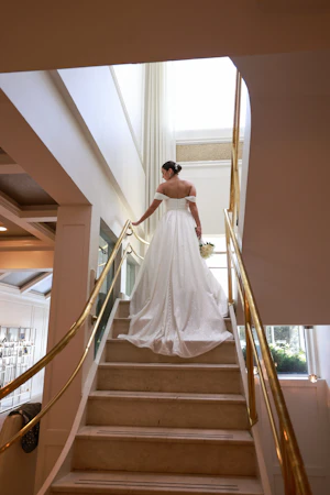 Bride wearing Anniston wedding dress by Sottero and Midgley walking up the stairs