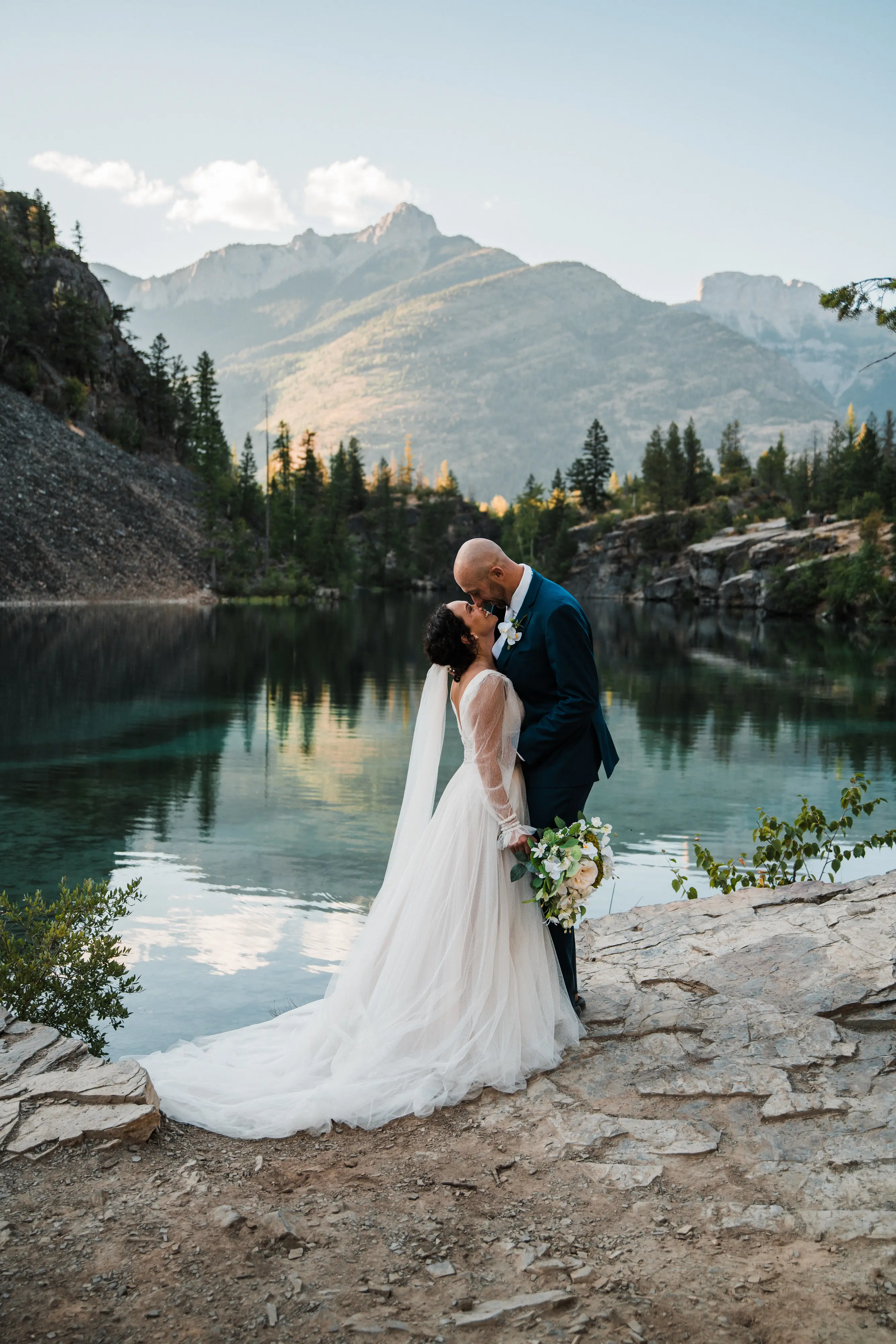Groom with Bride in Mountains Wearing Boho Wedding Gown Called Joanne by Rebecca Ingram.