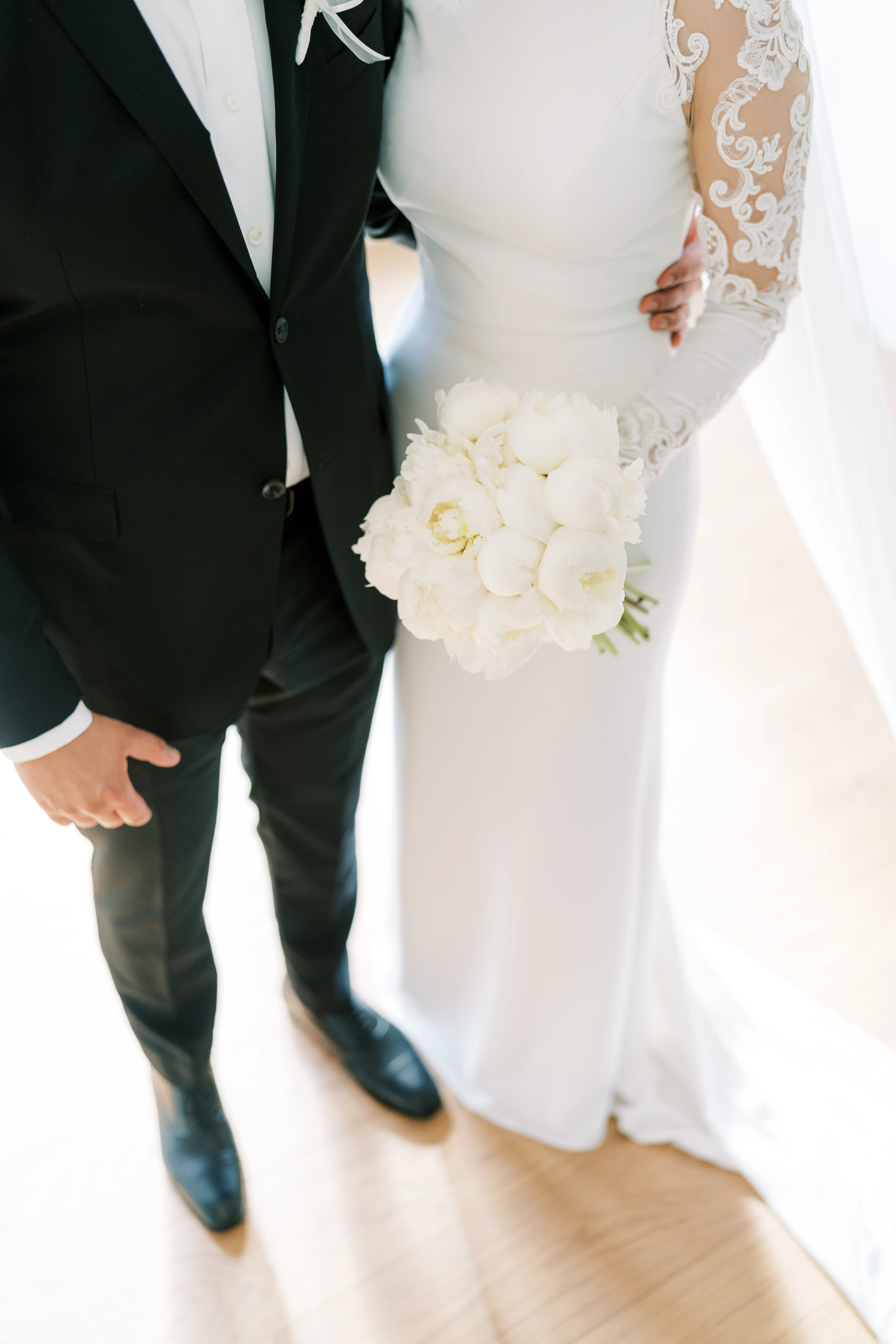 Bride Wearing Simple Long Sleeve Wedding Dress Called Bethany By Rebecca Ingram Holding White Flower Bouquet With Groom