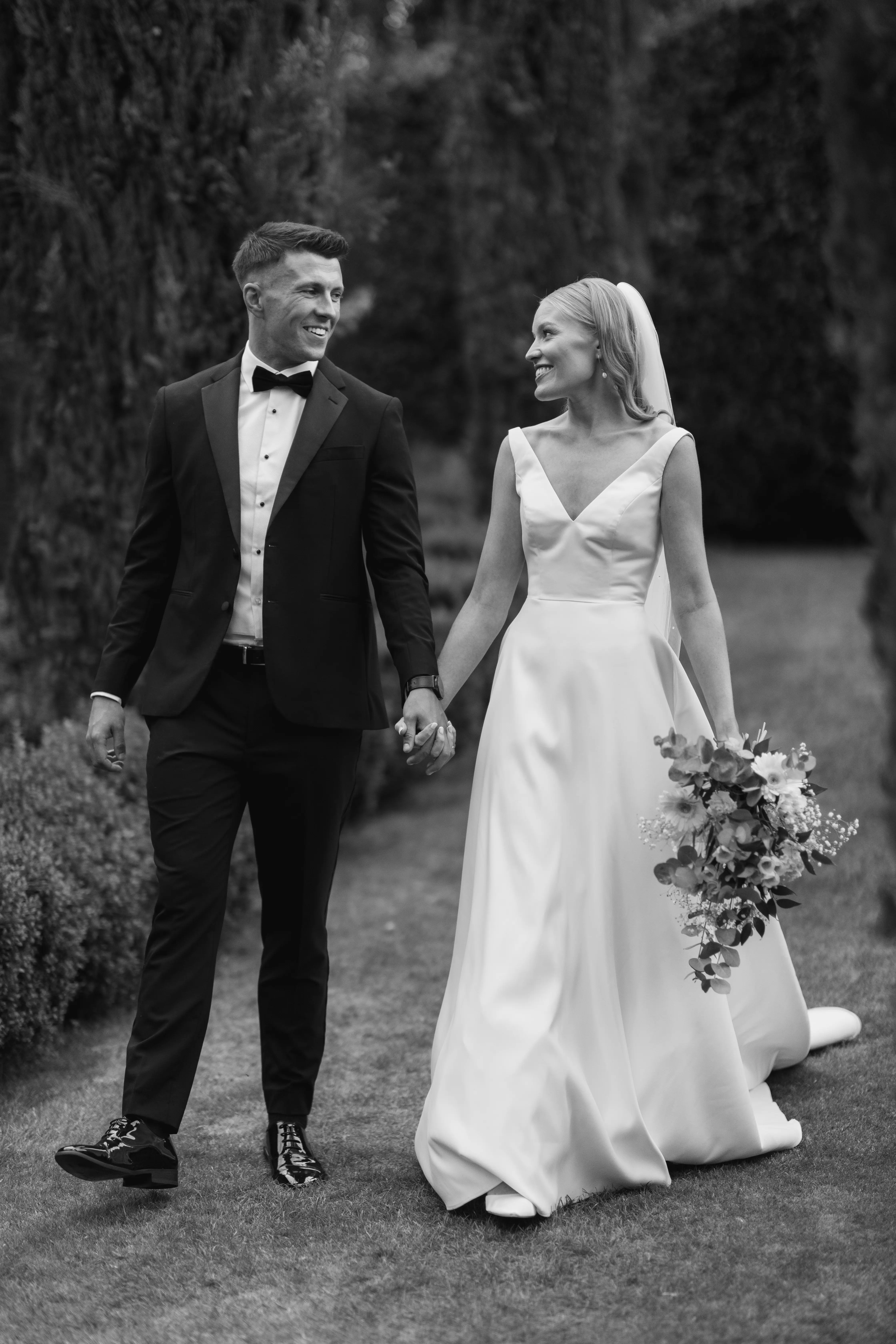 Bride wearing Paxton by Maggie Sottero walking with her husband while holding hands