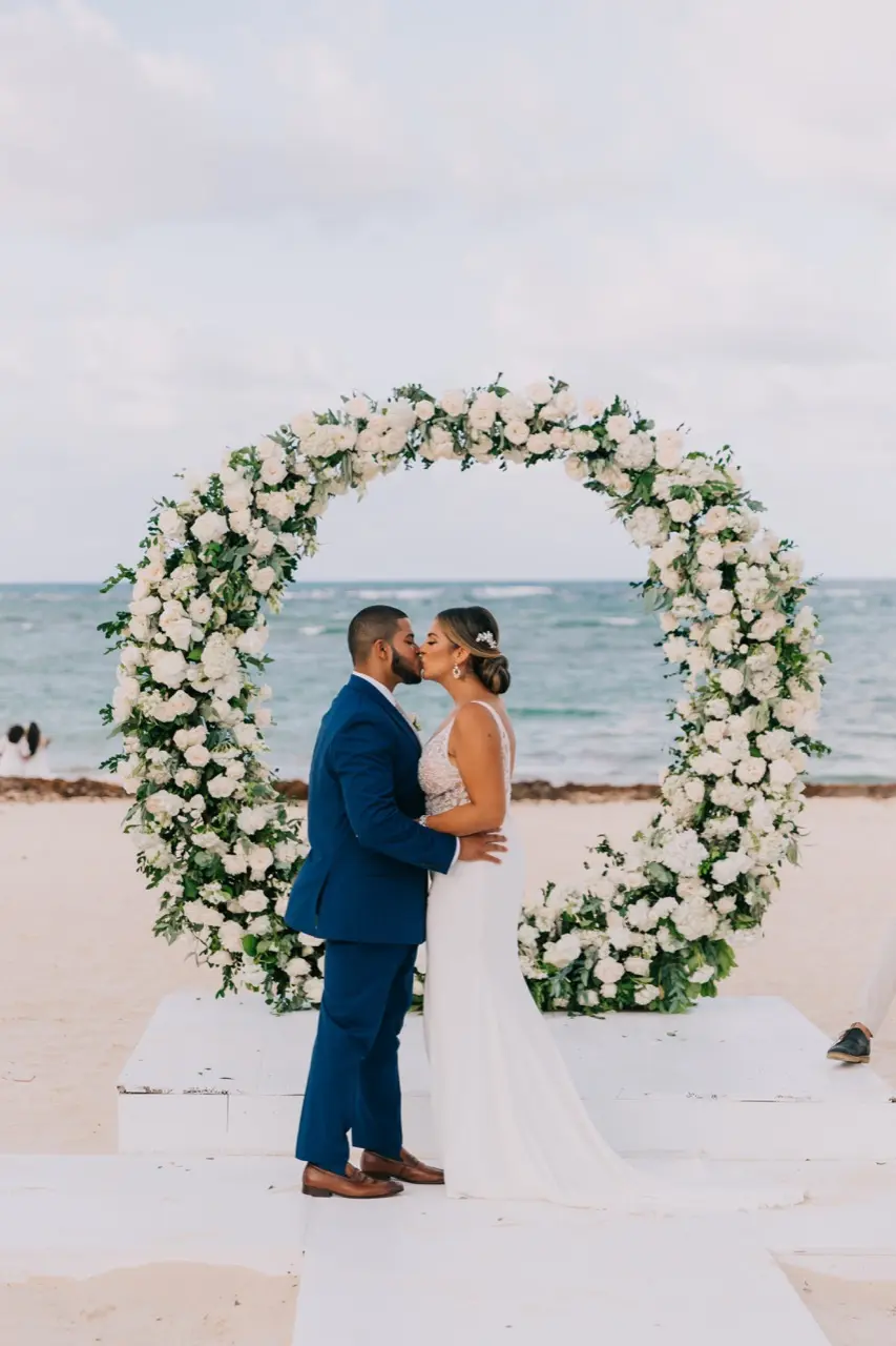 Bride and groom kissing with the seaside behind them.