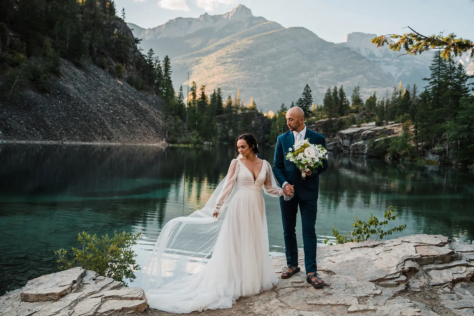 Groom Holding Hands with Bride in Front of Lake Wearing Vintage Gown Called Joanne by Rebecca Ingram.