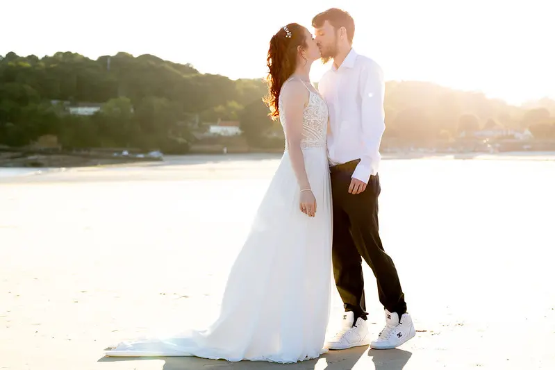 Bride Wearing Affordable Sheath Wedding Dress Called Lorraine By Rebecca Ingram Kissing The Groom