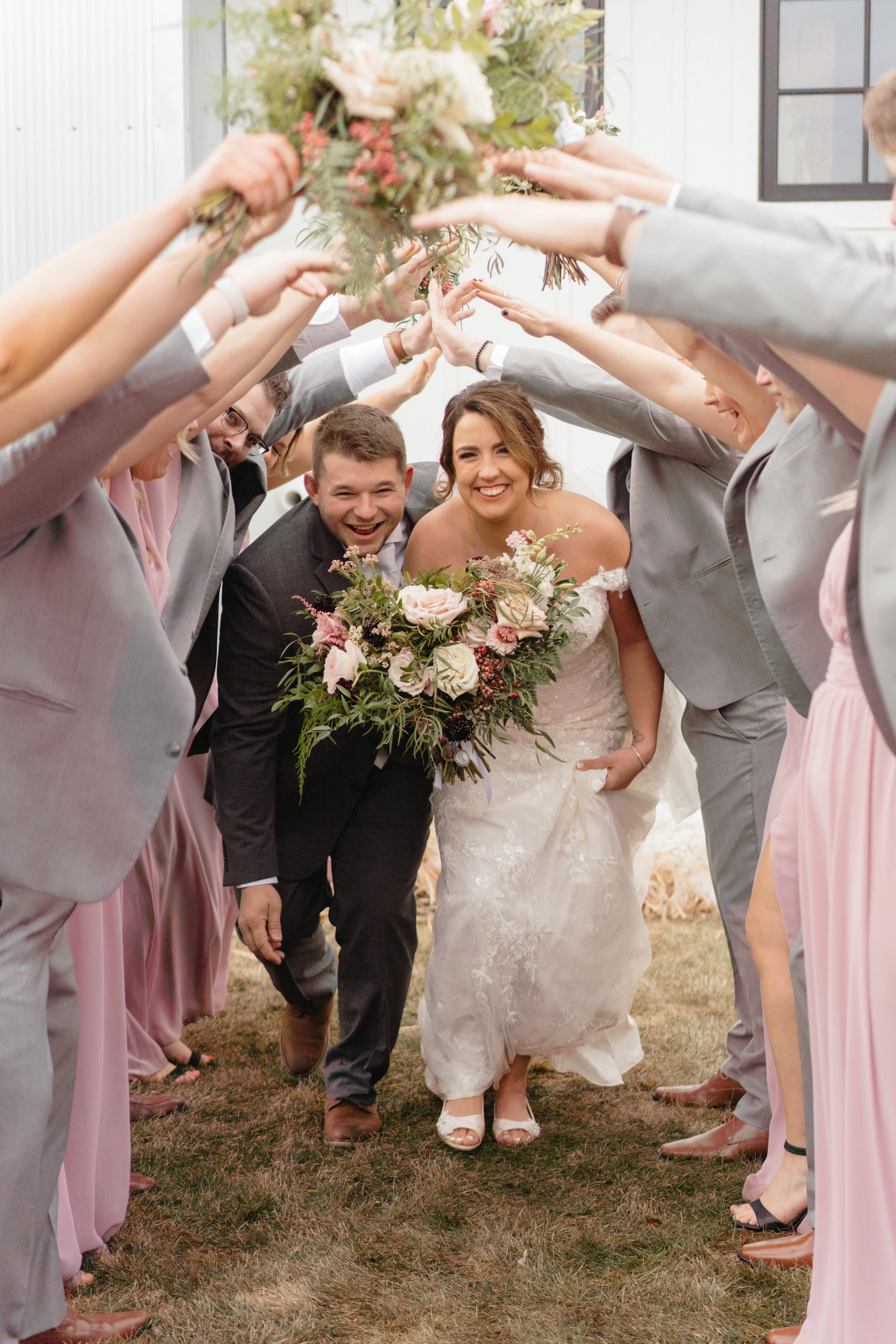 Bride Wearing Lace Beaded Wedding Dress Called Charmaine By Maggie Sottero And Groom Walking Through Their Bridal Party Bridge