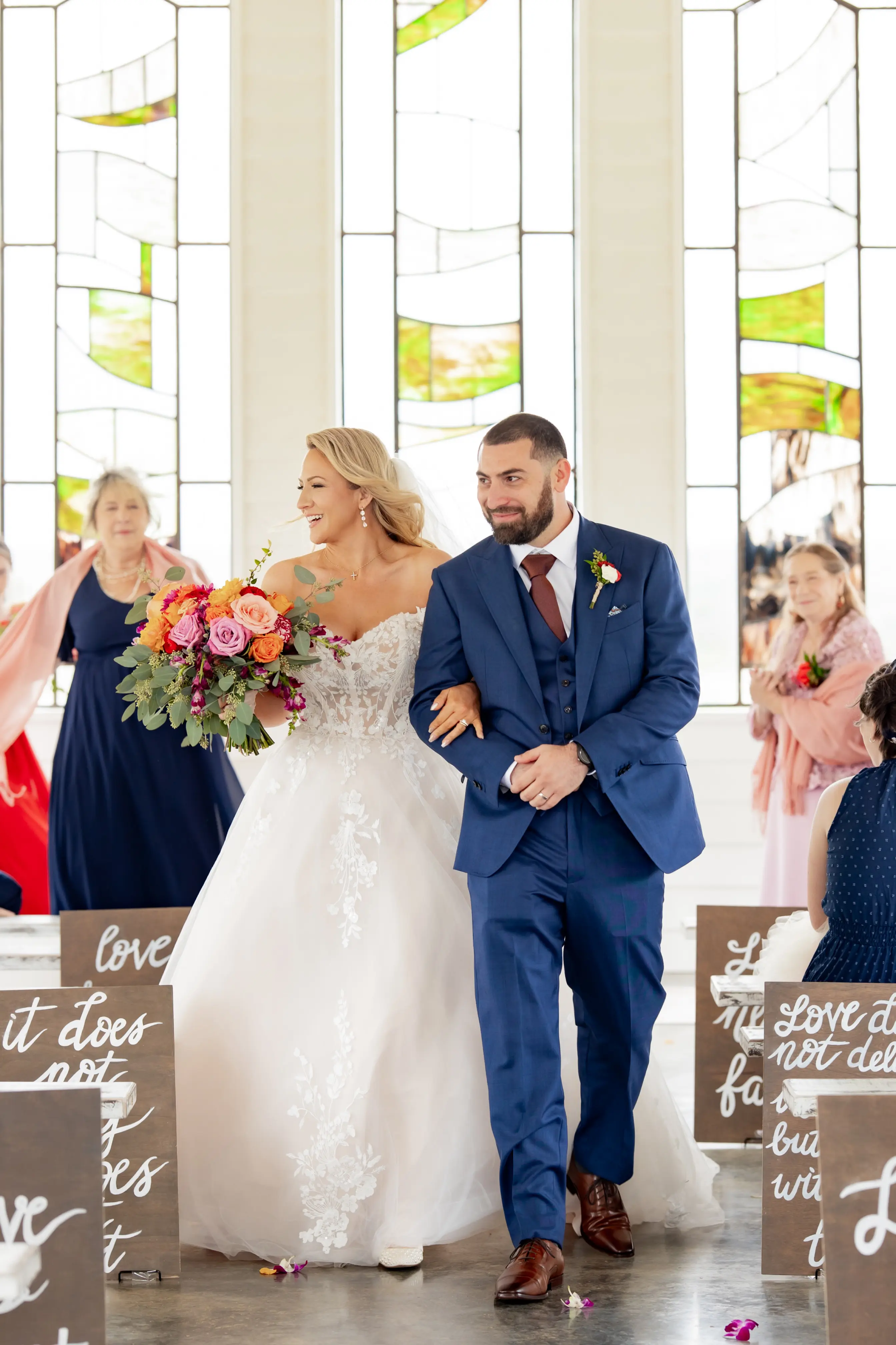 Bride wearing Harlem by Maggie Sottero walking down the aisle with her husband