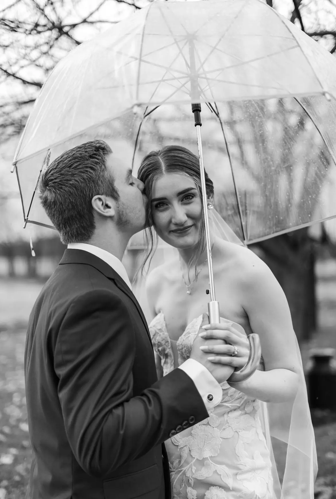 Bride And Groom Posing Under Umbrella. Bride Wearing Strapless Wedding Dress With Oversized Floral Motifs Called Hattie By Rebecca Ingram