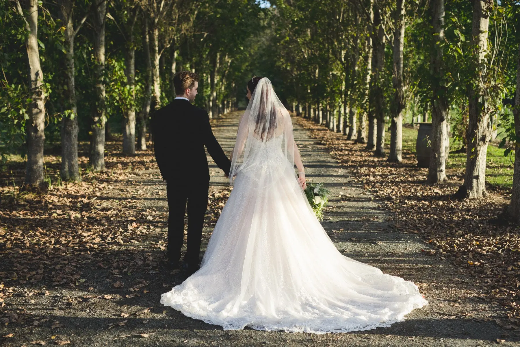 Groom Holding Hands with Bride in Lace Ball Gown Wedding Dress with Sequined Tulle and Lace Motifs over Bodice and Statement Hemline called Tristyn by Maggie Sottero