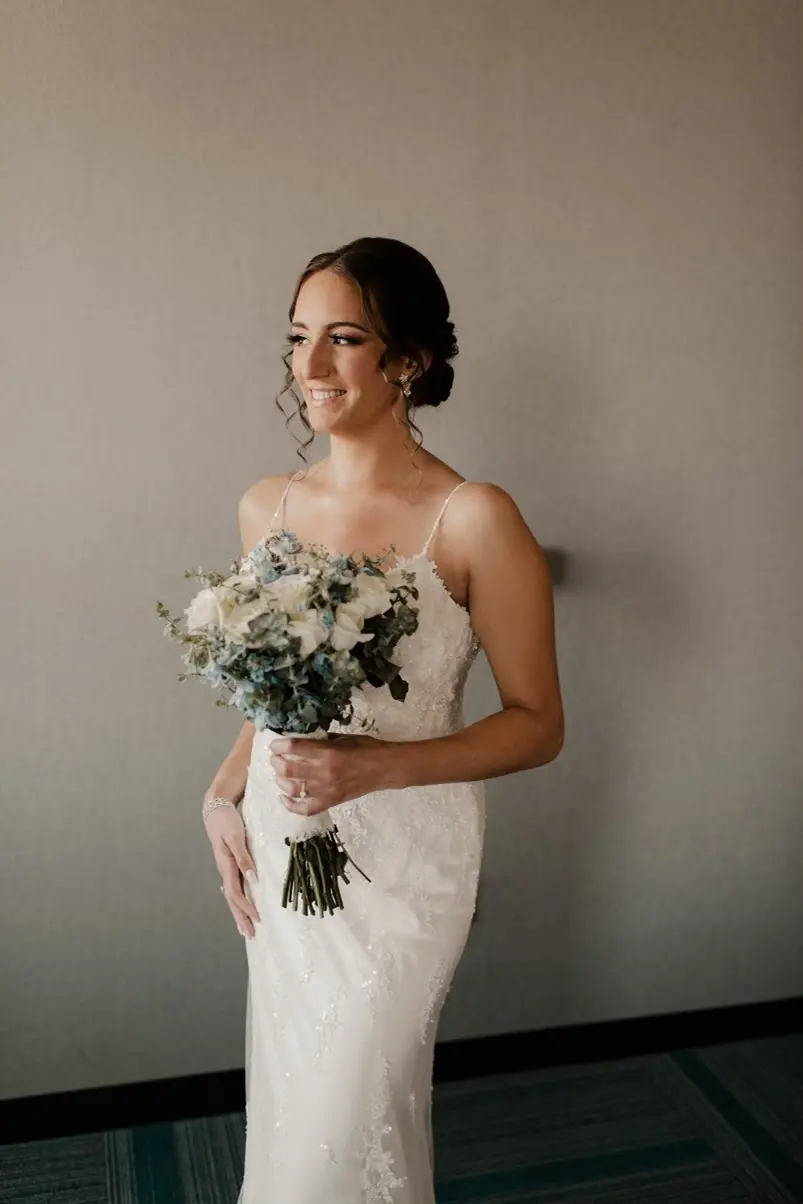 Bride wearing ivory dress holding all ivory bouquet of roses and greenery.