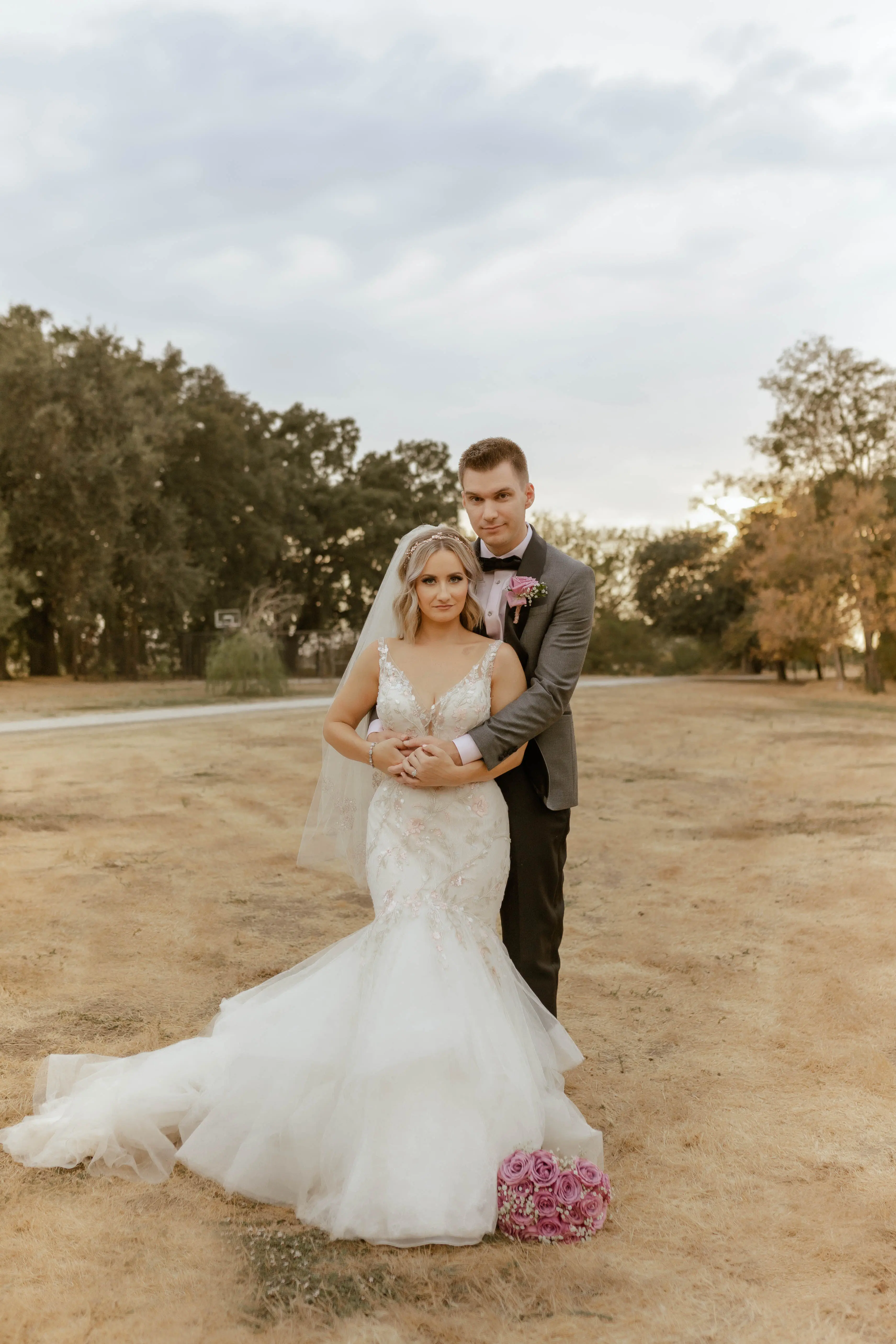 Bride Wearing Pink Lace Mermaid Wedding Dress Called Kenleigh By Sottero And Midgley With Groom In A Field