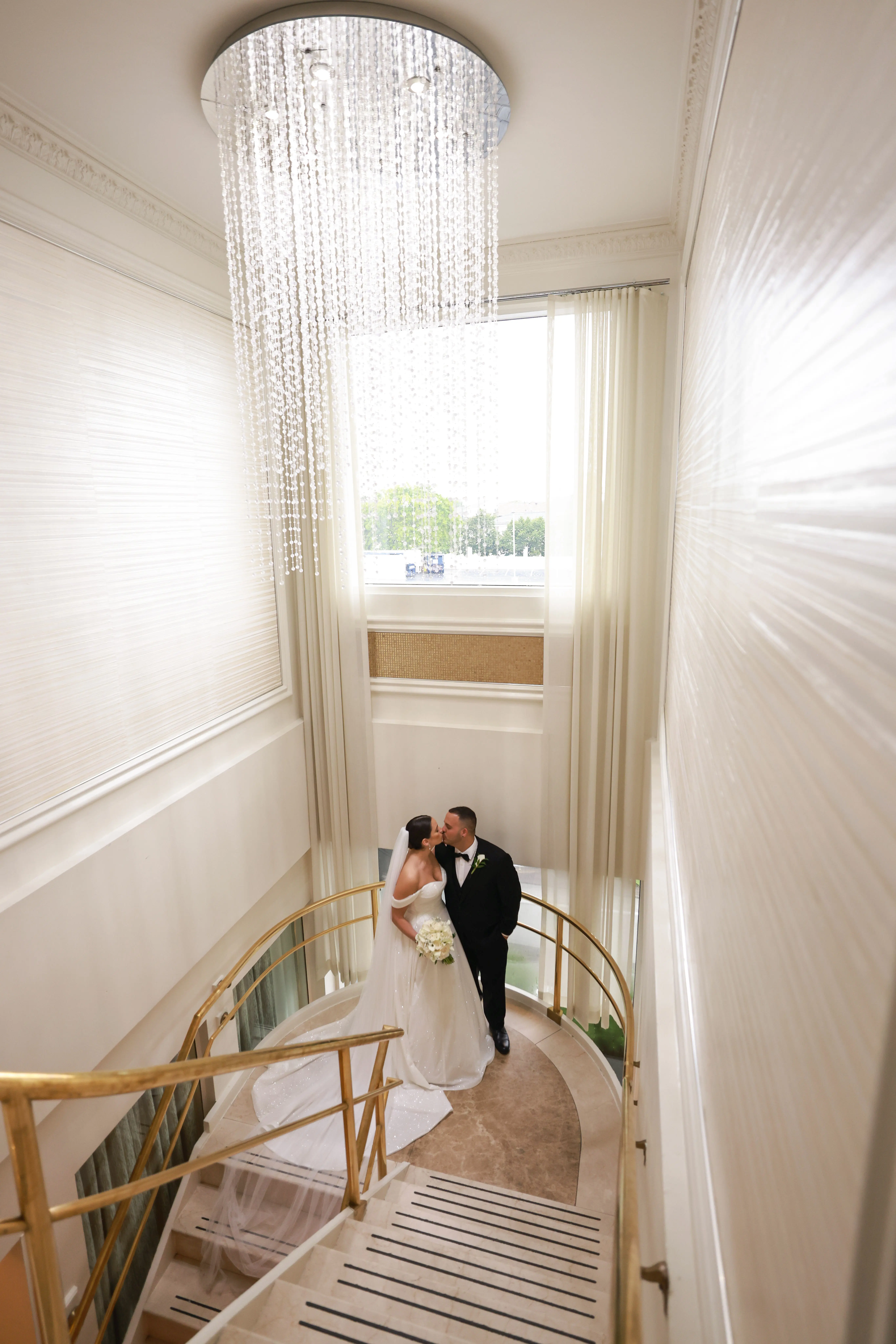 Bride wearing Anniston wedding dress by Sottero and Midgley on the stairs with her groom