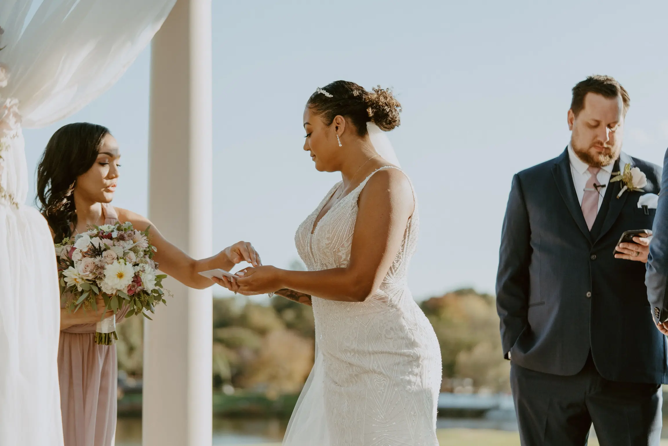 Bride with groom wearing art deco-inspired beaded wedding dress at outdoor venue.